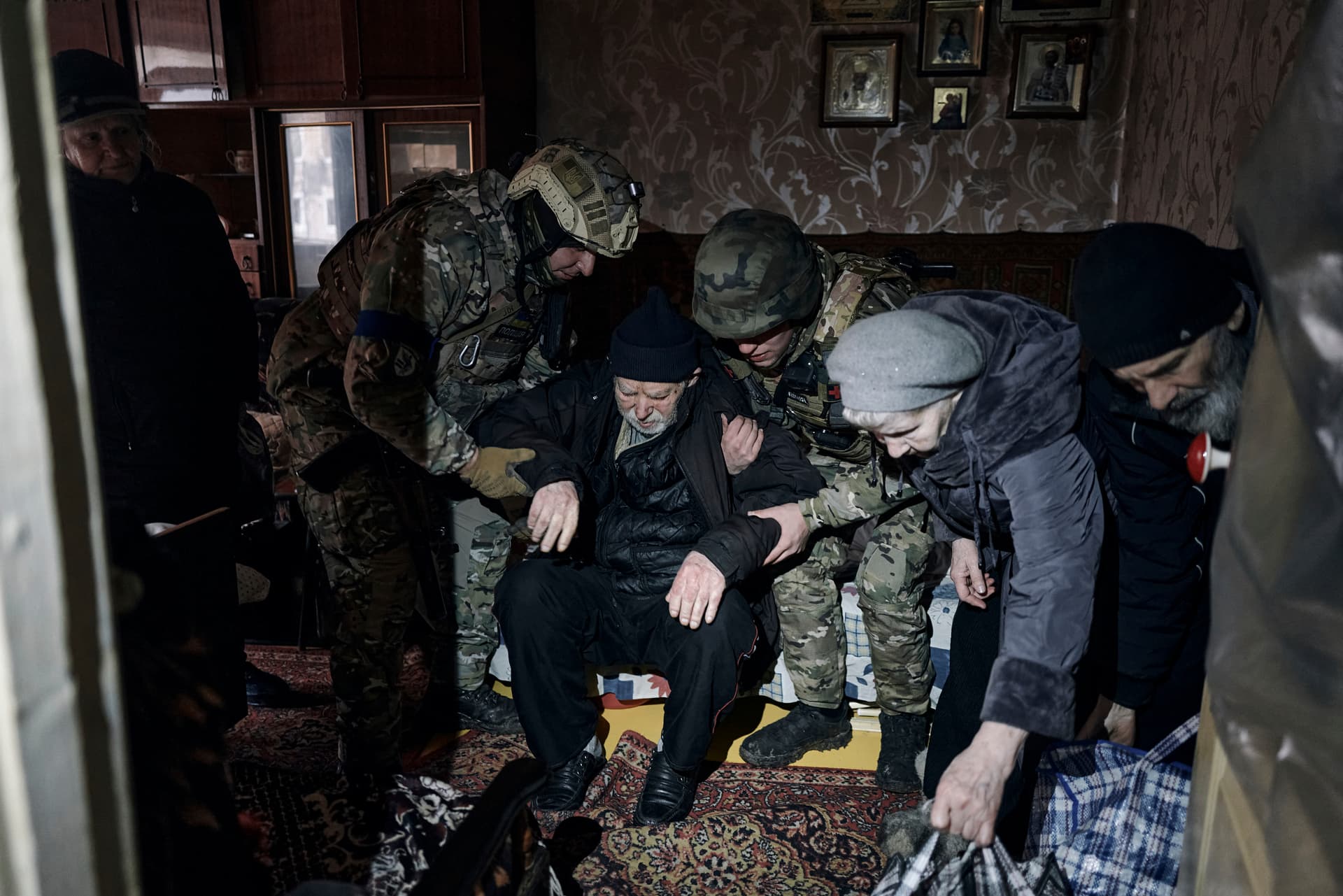 Police officers help en elderly disabled resident get into an evacuation car in war-hit Avdiivka