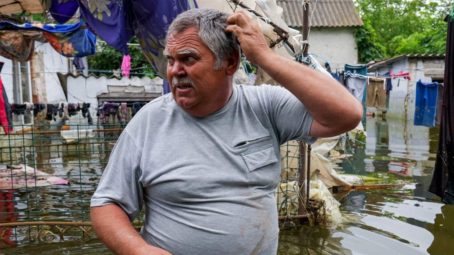 A local resident walks in flooded yard of his house in Afanasiyivka