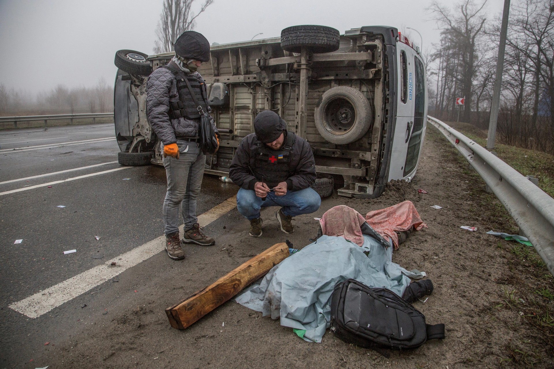 A volunteer inspects a corpse in the town of Bucha