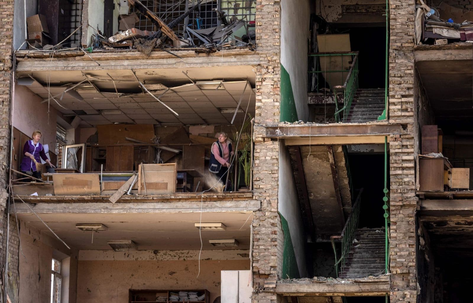 Women clean inside a damaged building in Vyshneve