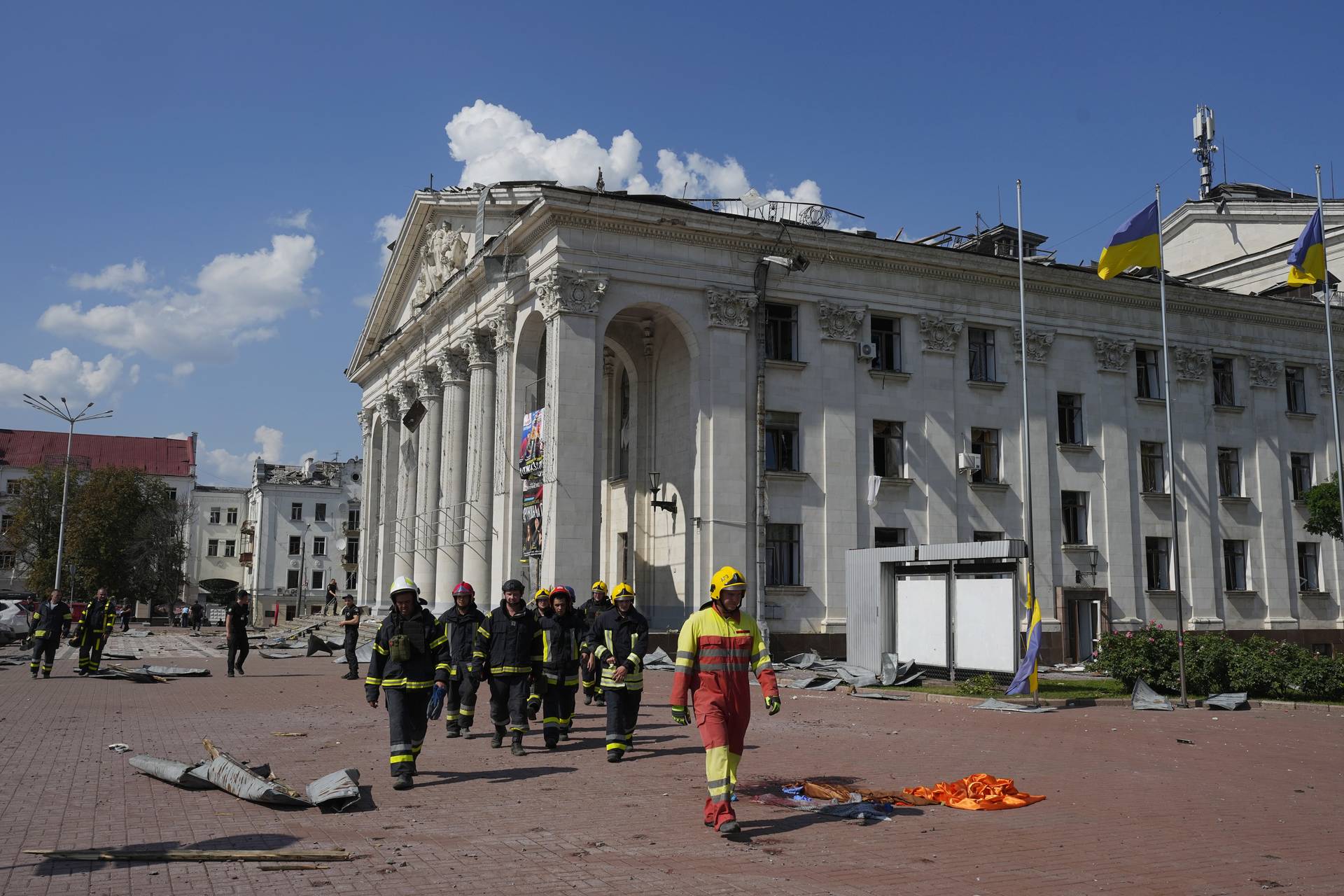 Firefighters walk next to the Chernihiv Drama Theatre damaged by a Russian attack in Chernihiv