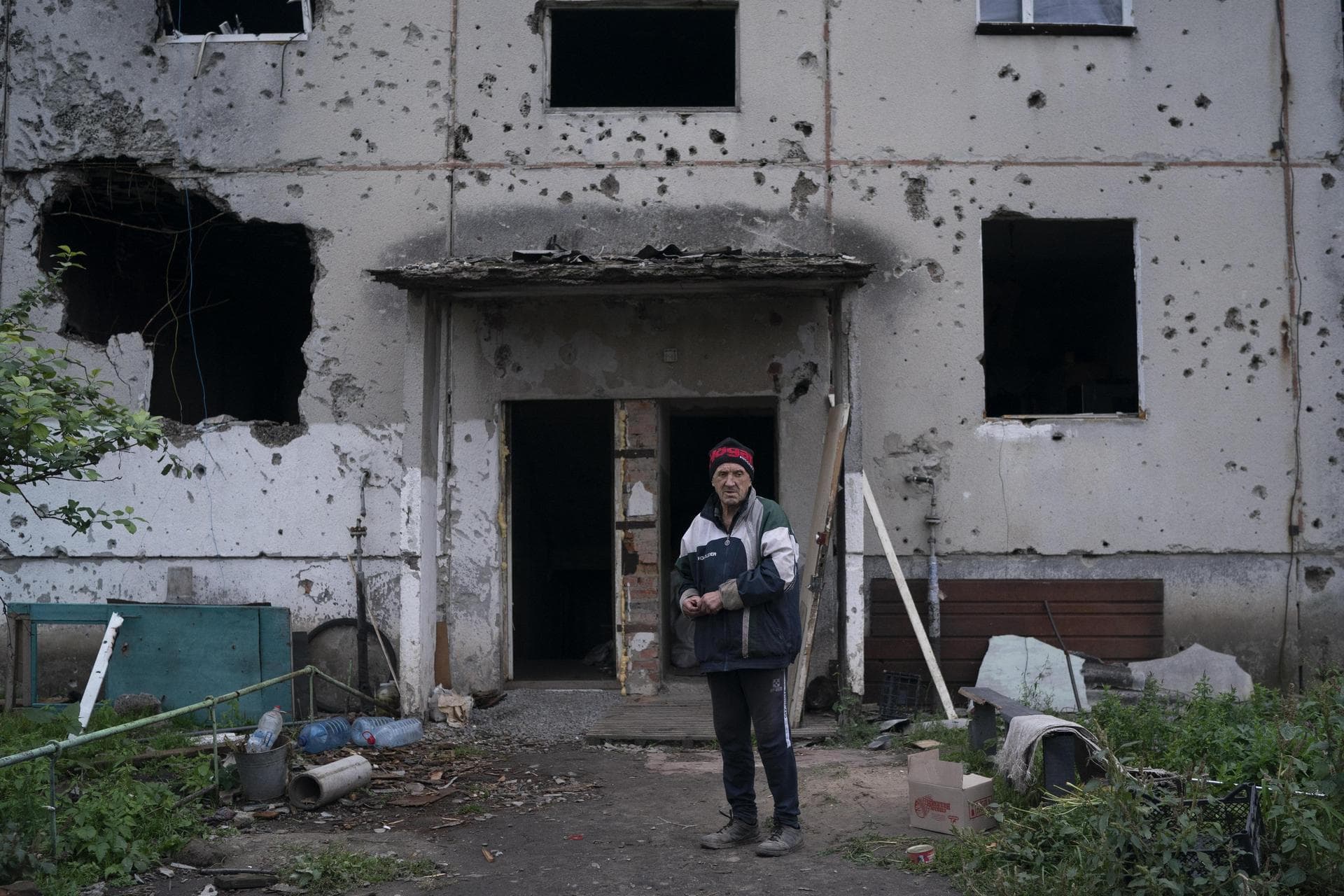 Oleh Lutsai stands in front of the entrance of the damaged building where he lives in the freed village of Hrakove