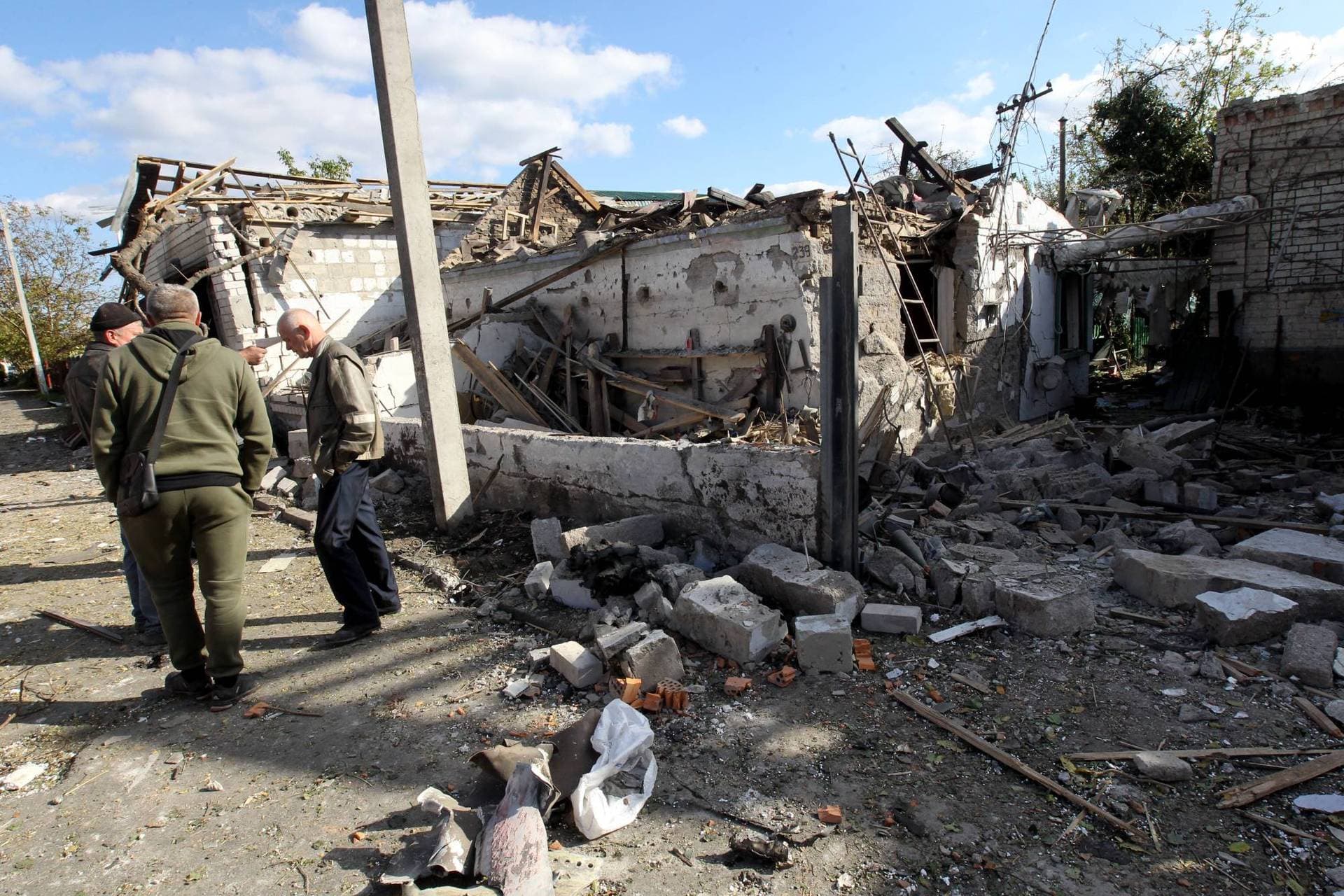 Men stand outside a house destroyed in the Russian rocket attack in Obukhivka