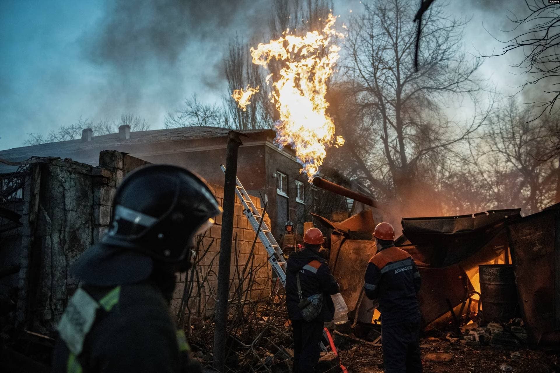 Rescuers work to put out a fire outside a damaged residential building in Donetsk