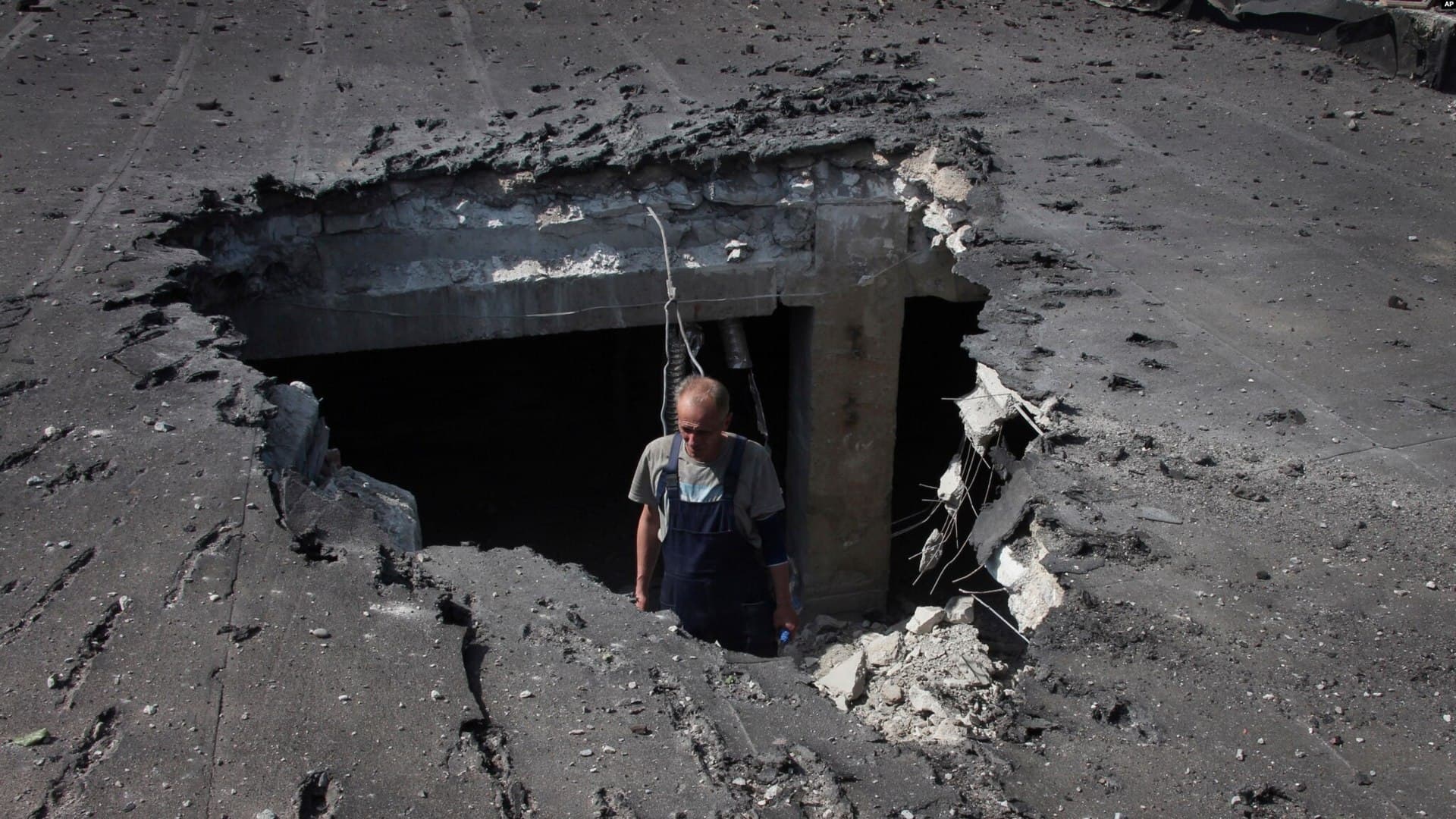 A man examines the roof of a hospital damaged during shelling in Donetsk