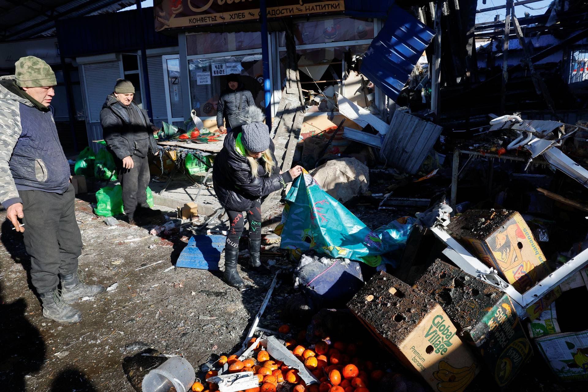 People remove debris at a Donetsk food market following a blast