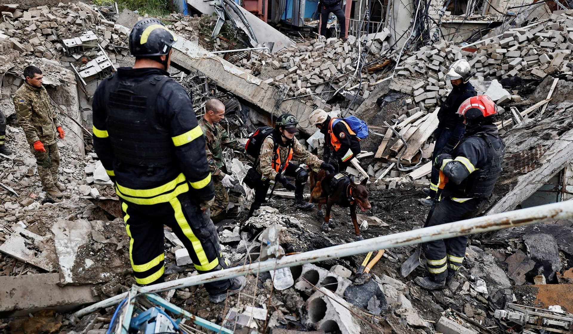 Firefighters and Ukrainian army soldiers search for bodies of people killed during a Russian attack among the remains of a building beside a TV tower in the recently liberated town of Izium