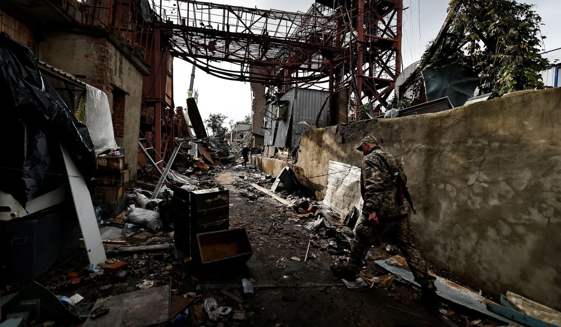 A Ukranian army soldiers walks where firefighters and Ukrainian army solders search for bodies of people among remains of a building in the recently liberated town of Izium