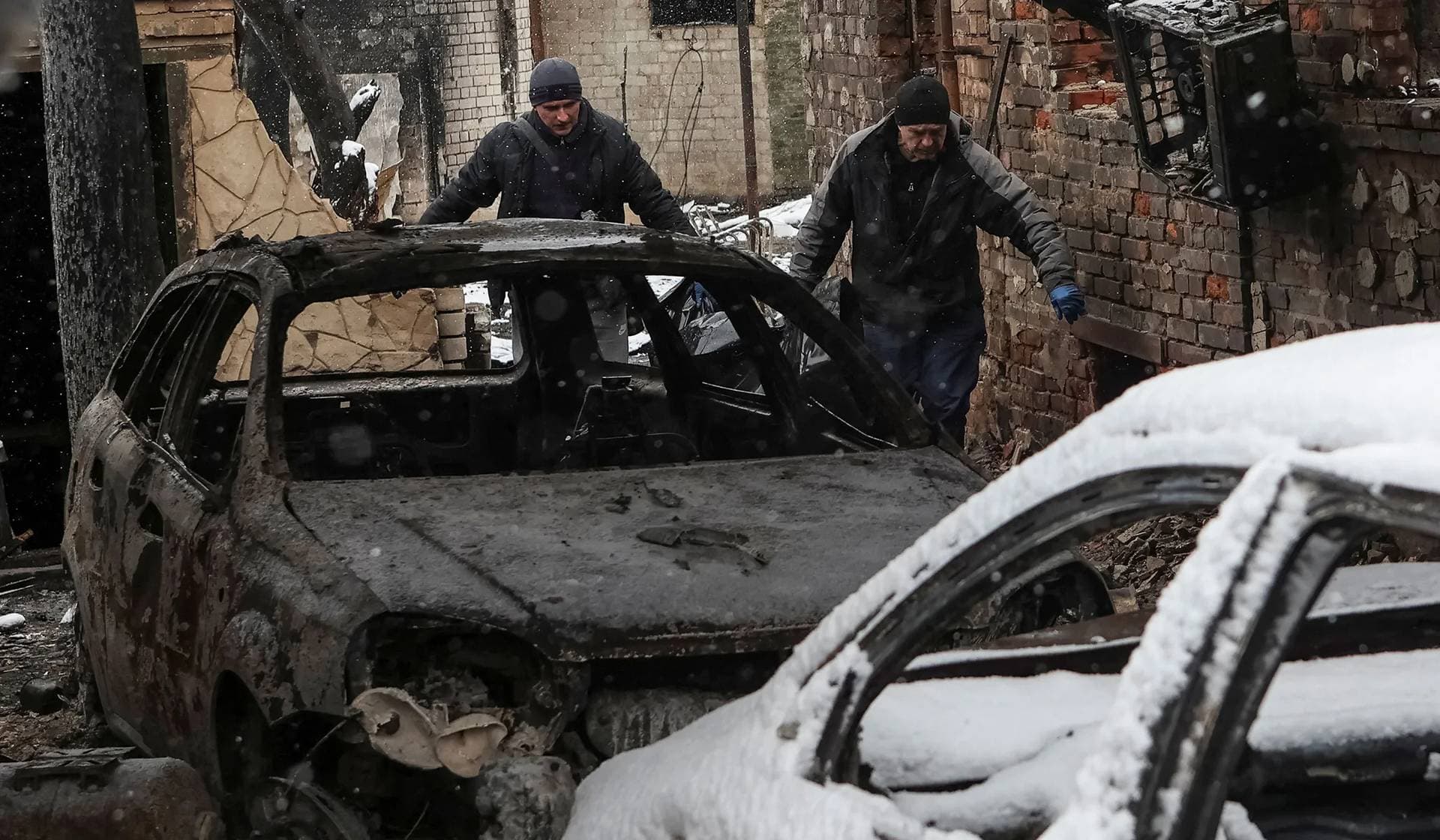 Workers evacuate the body of a local resident from a burned house at the site of a Russian drone strike in Kharkiv