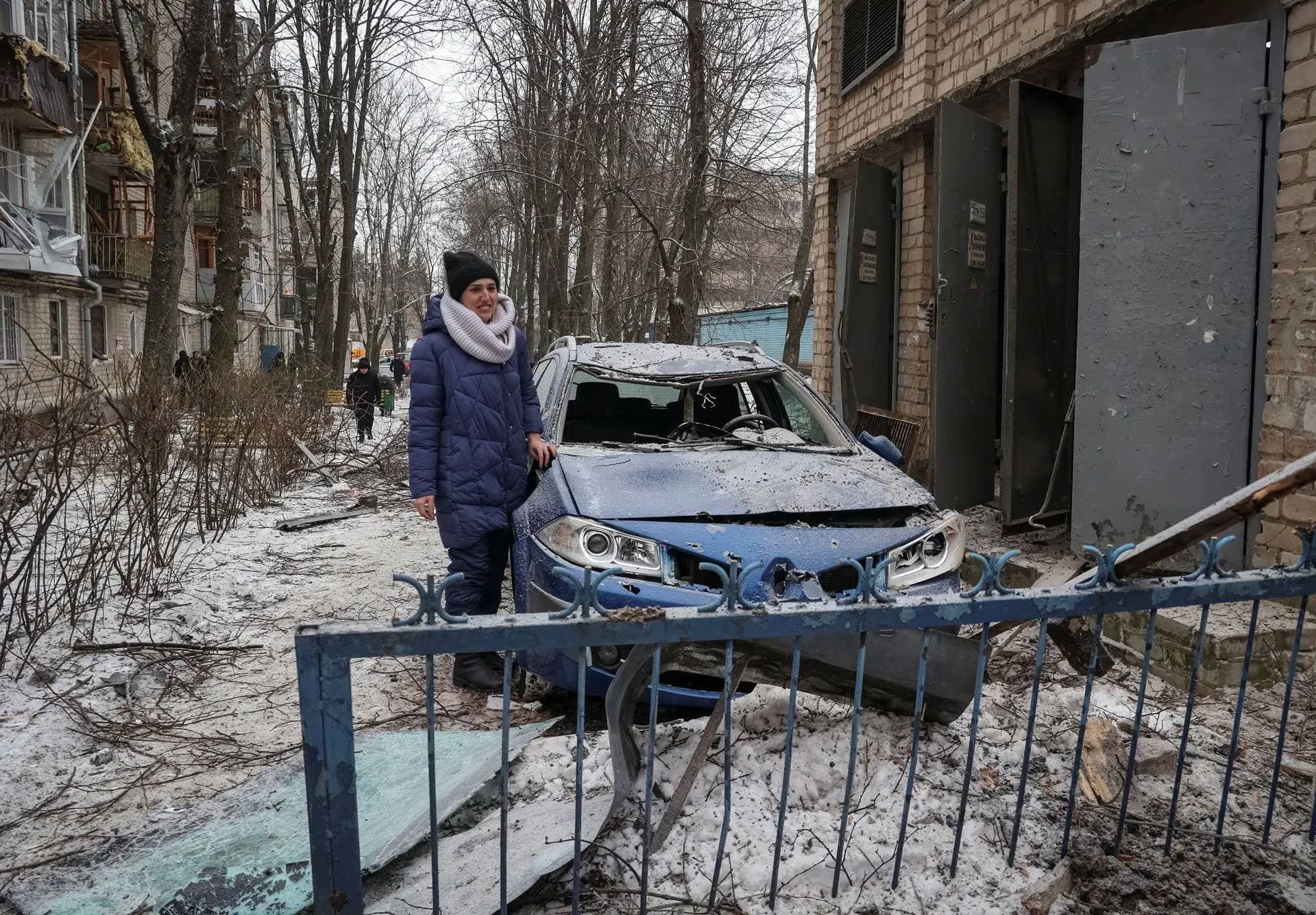 A resident stands near a destroyed car at the site of an apartment building damaged during a Russian missile strike in Kharkiv