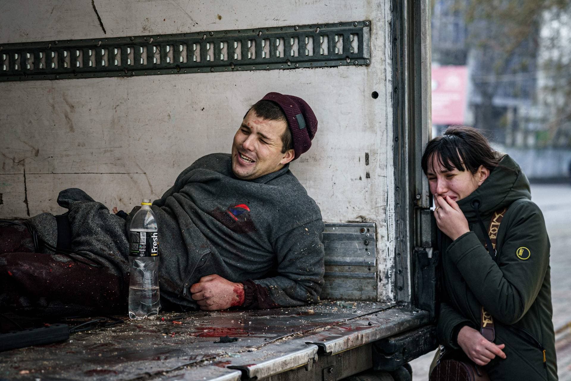 A woman reacts next to an injured man after Russian shelling to Ukrainian city of Kherson