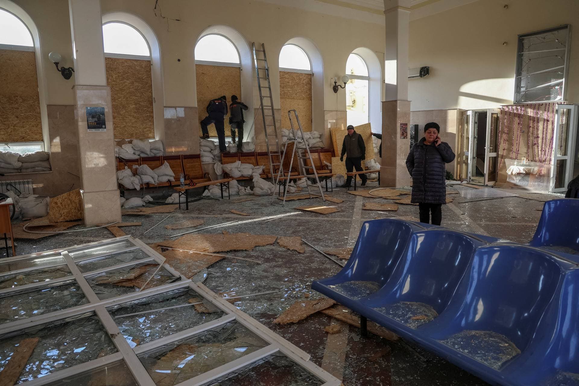 Workers clean up an area of the train station following the attack in Kherson