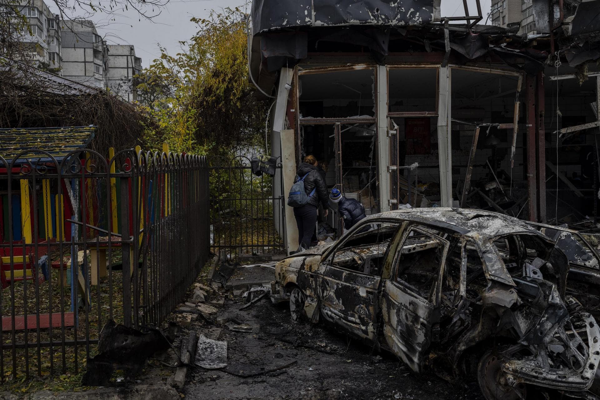 Residents check the damage of a shop destroyed a day earlier during a Russian attack in Kherson