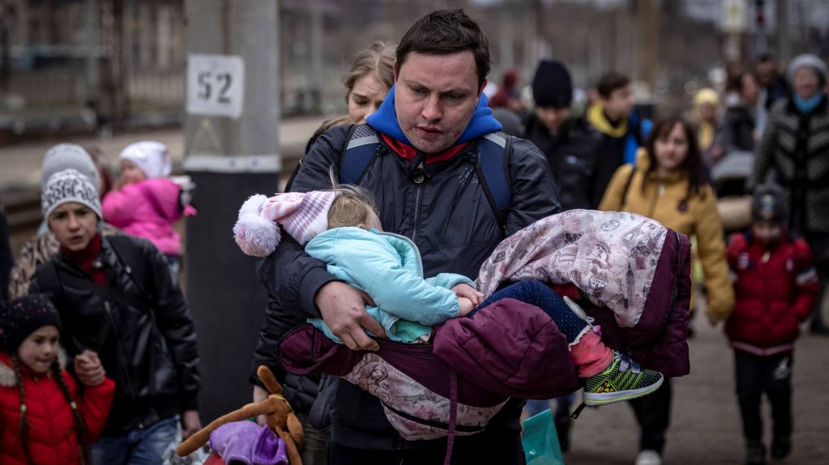 A man carries a little girl as he arrives with other families to board a train at Kramatorsk central station