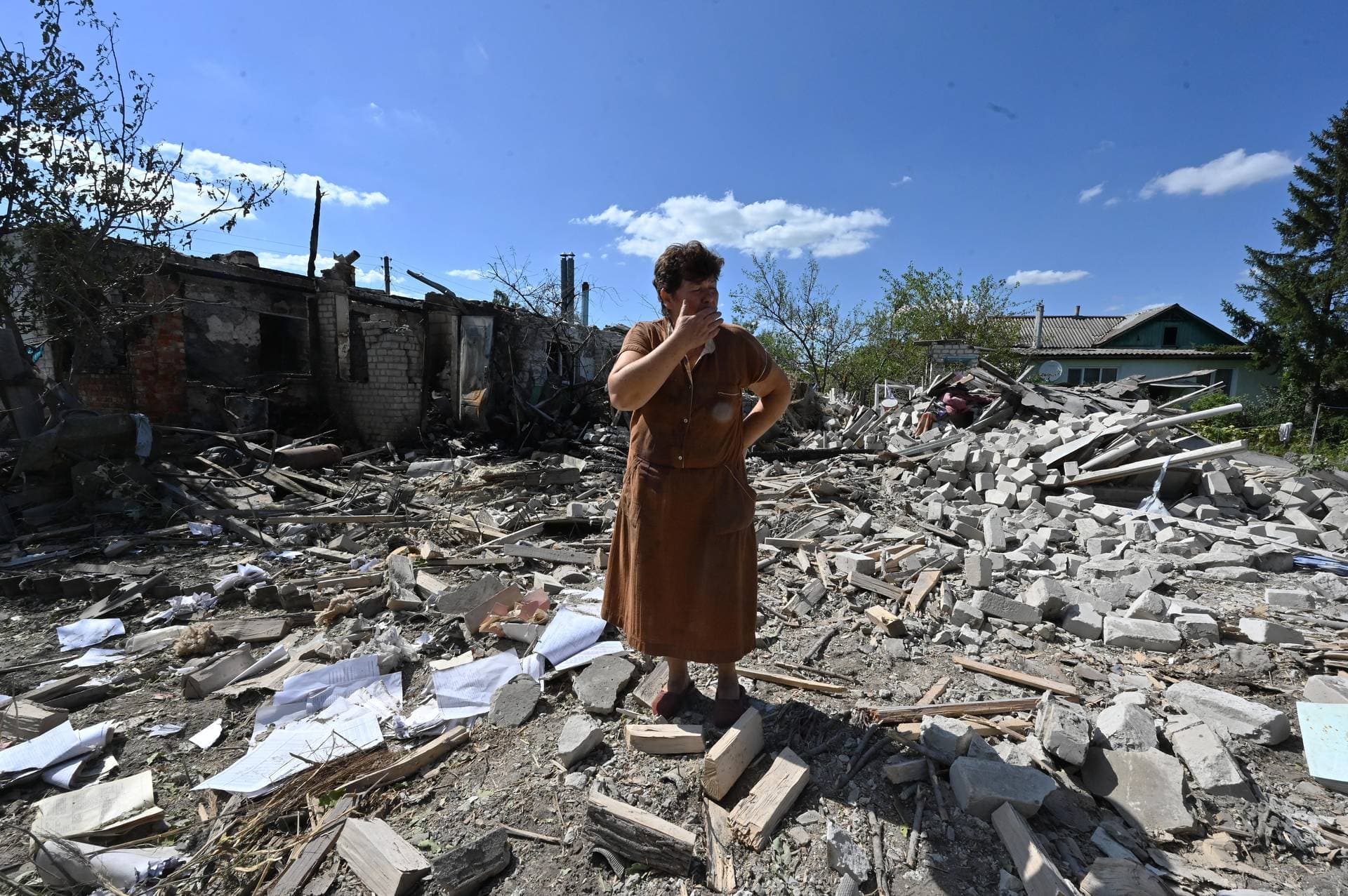 A woman stands among the debris of her neighbour’s house destroyed by shelling in the village of Zaoskillya