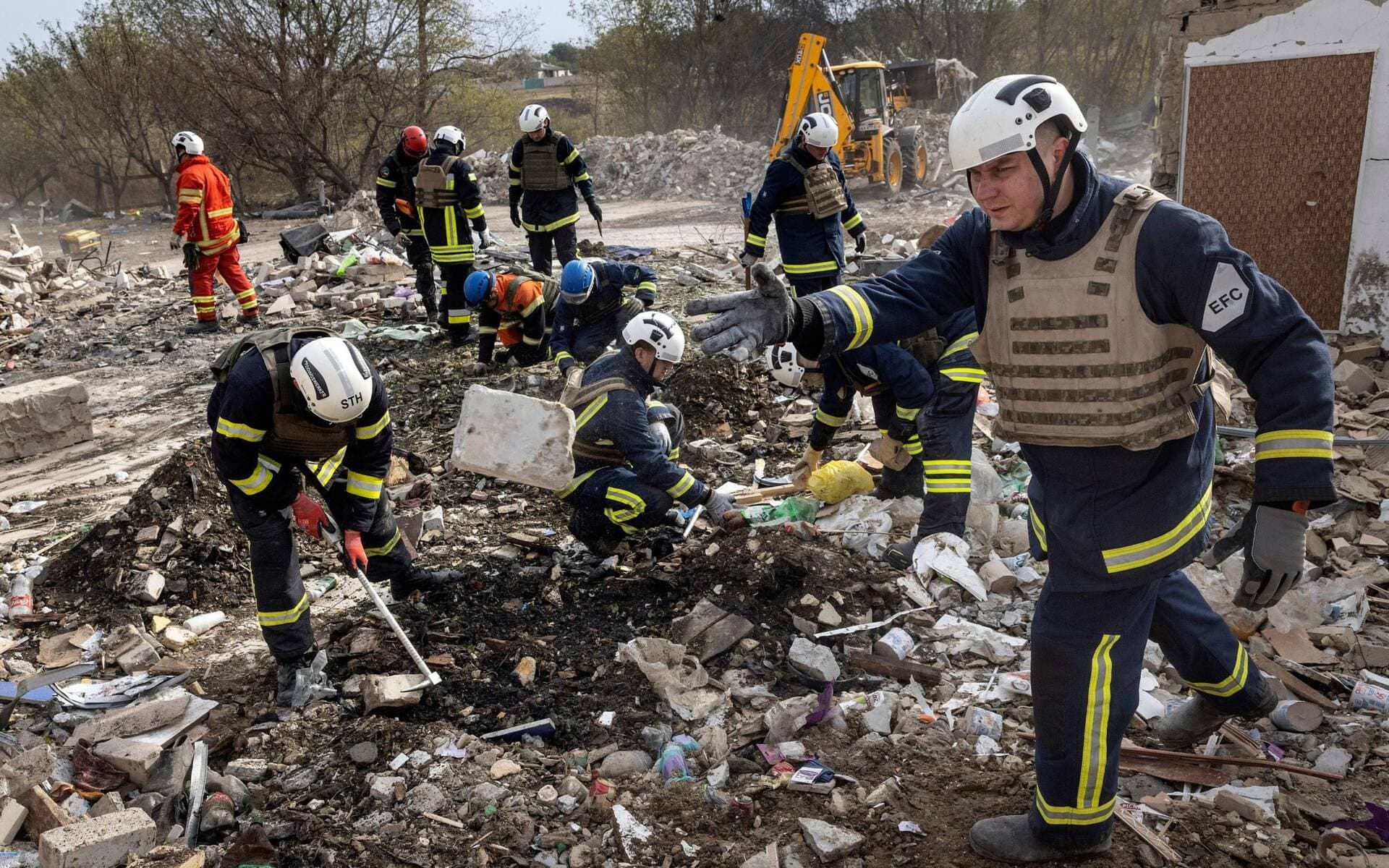 Rescue workers dig through the rubble at the site of a missile attack in the village of Hroza, near Kharkiv