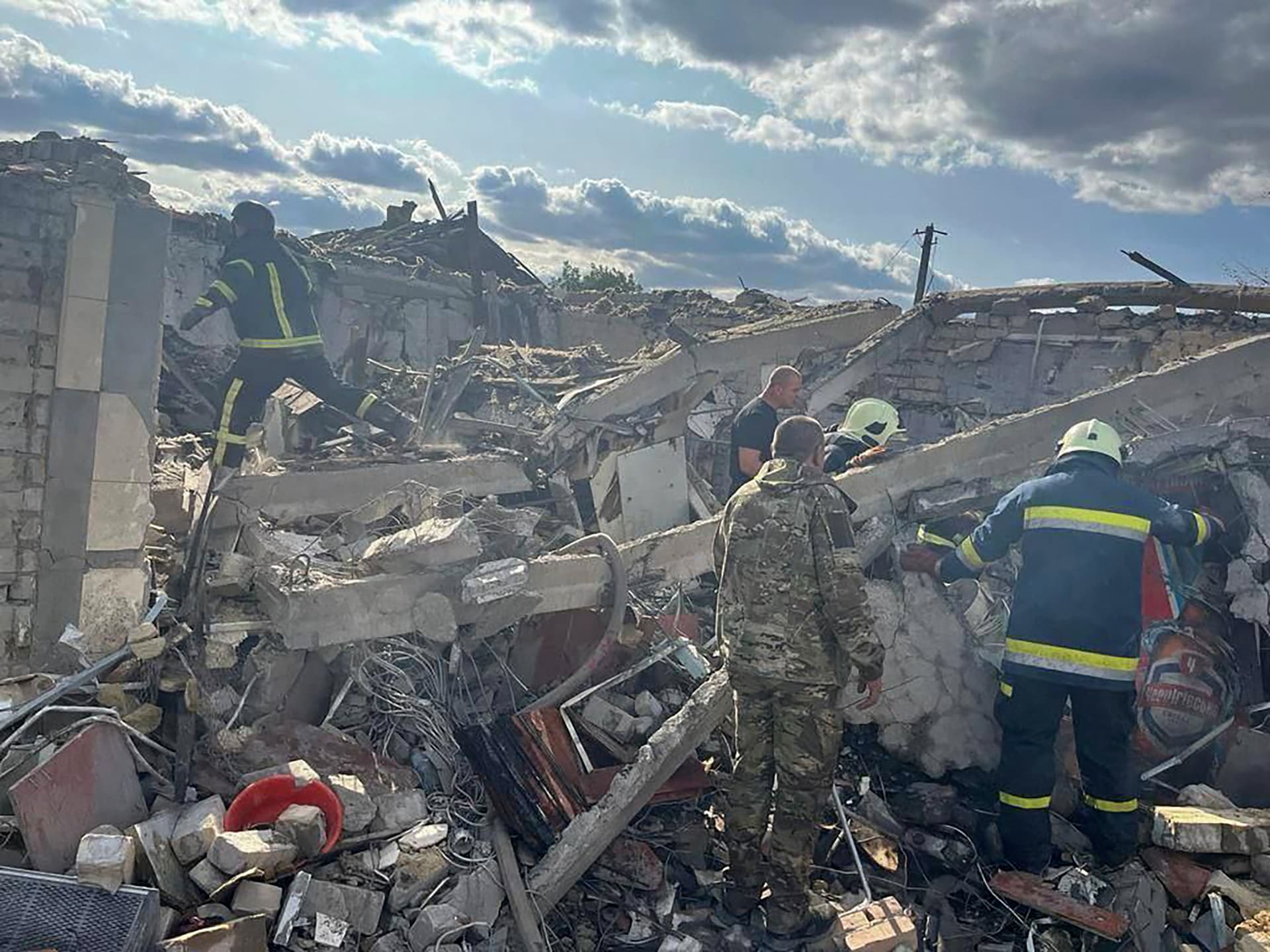 Rescuers work at a site of a Russian military strike in the village of Hroza