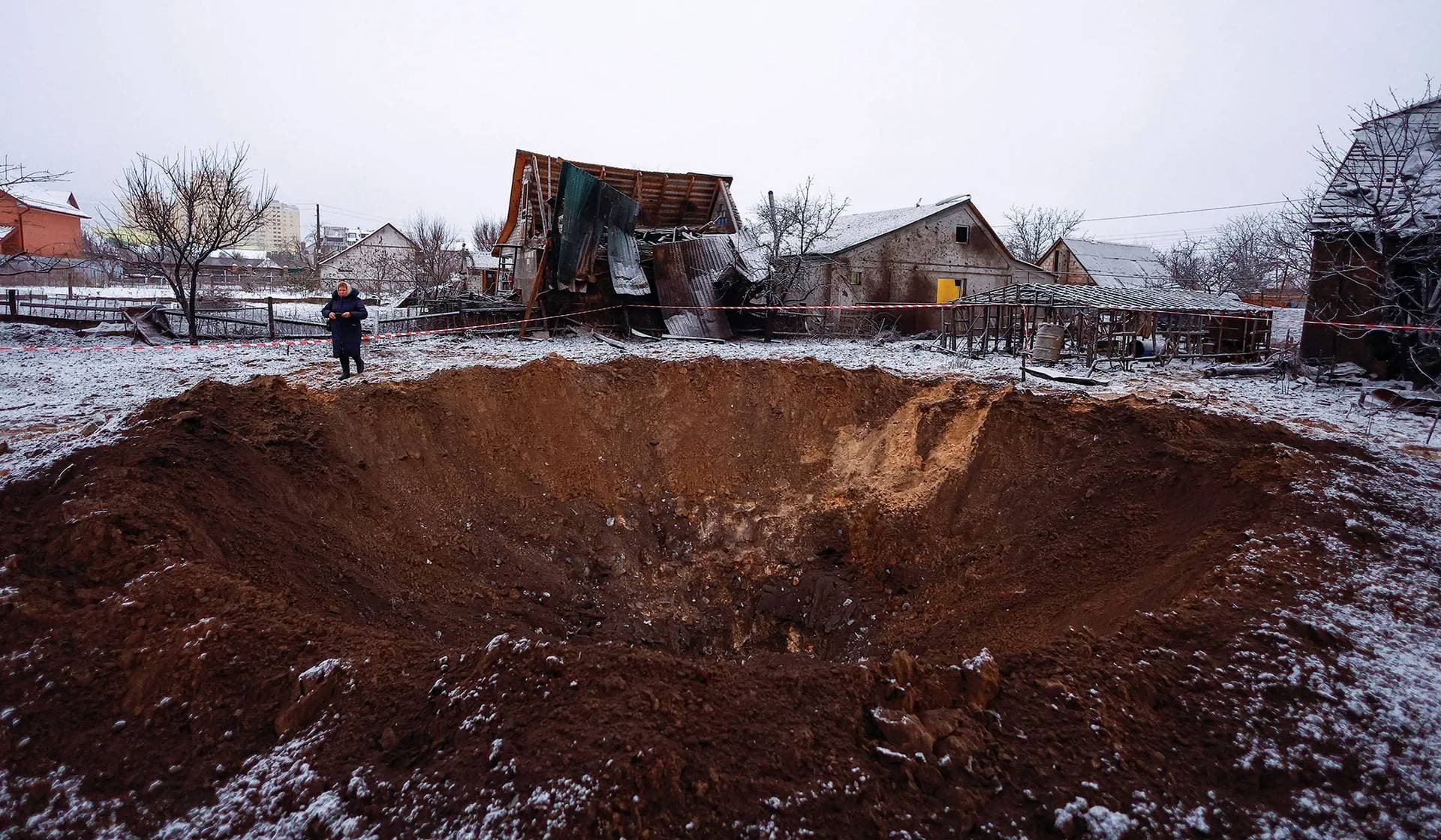 A local resident stands next to a crater at a site of a Russian missile strike in Kyiv