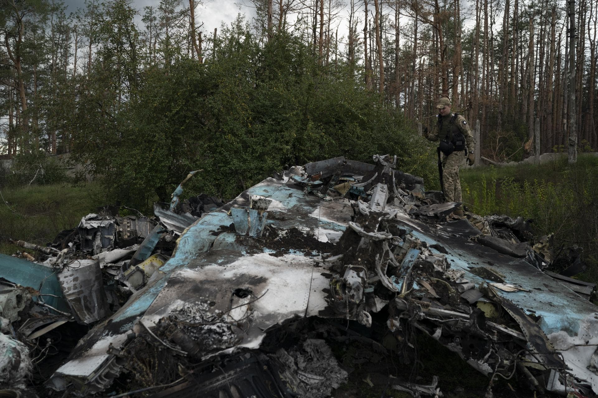 A Ukrainian serviceman walks over the remains of Russian aircraft SU-34 in an area at the recaptured town of Lyman