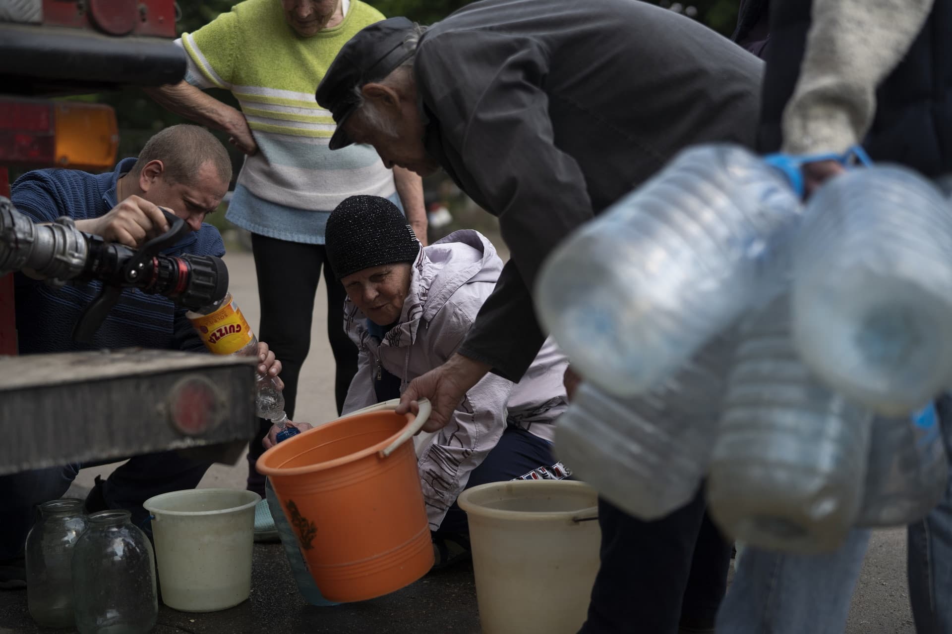 People gather to fill cans with water from a firefighters truck in Lysychansk