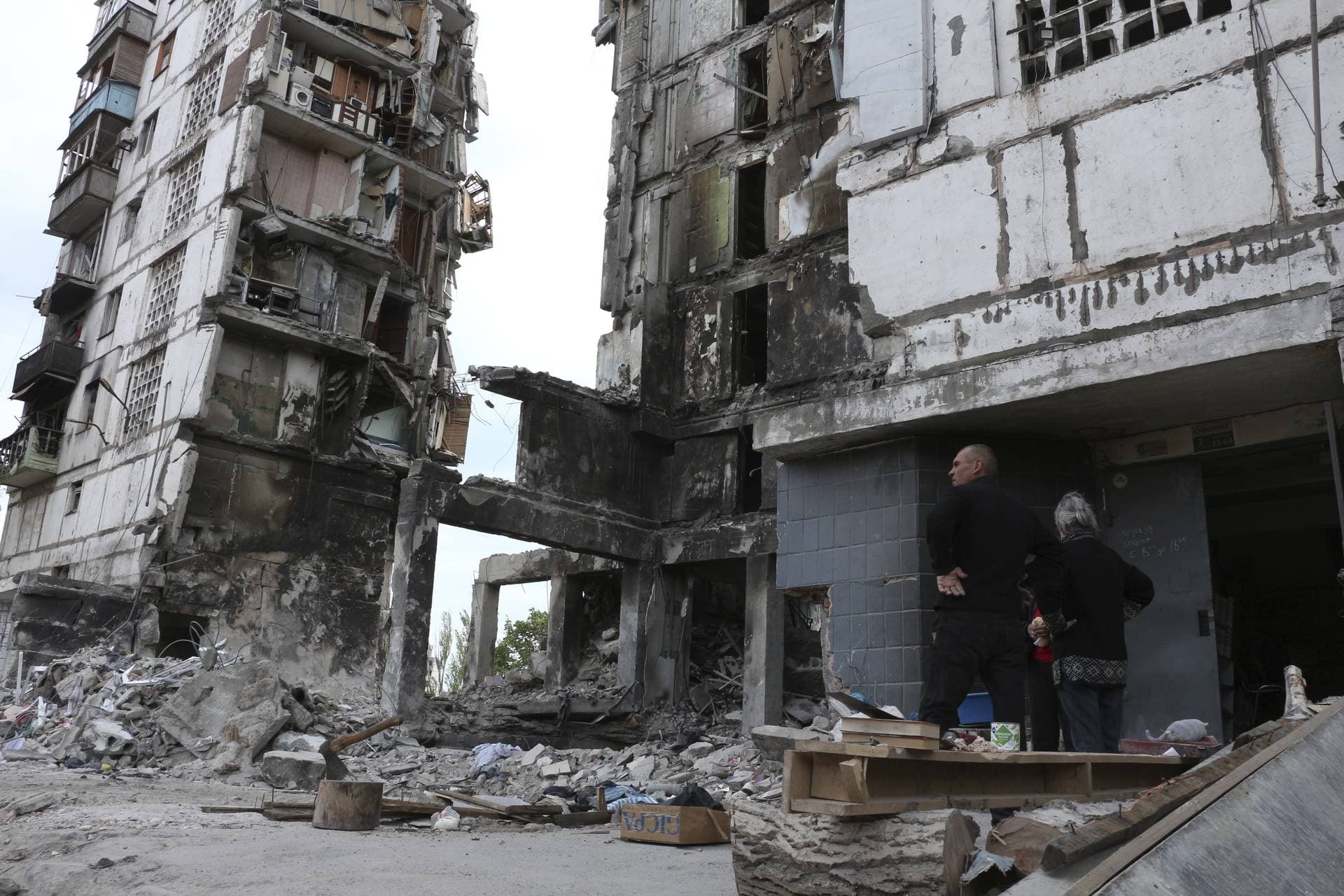 Local residents stand at the side of damaged during a heavy fighting buildings in Mariupol