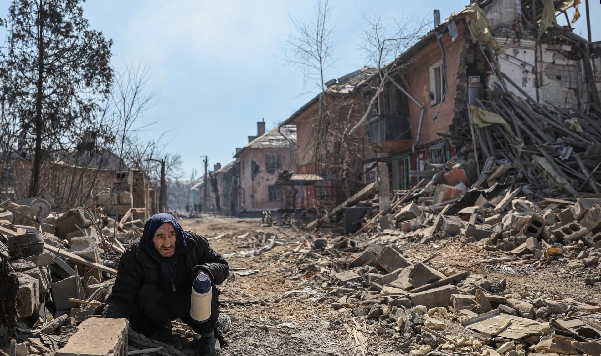 A man crouches amid the rubble in the Livoberezhnyi district of Mariupol