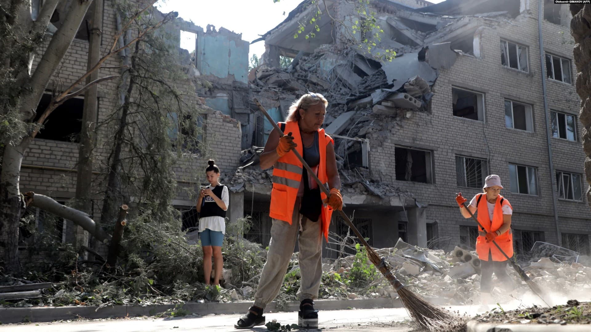 Workers clean up outside a building destroyed as a result of Russian shelling in Mykolayiv
