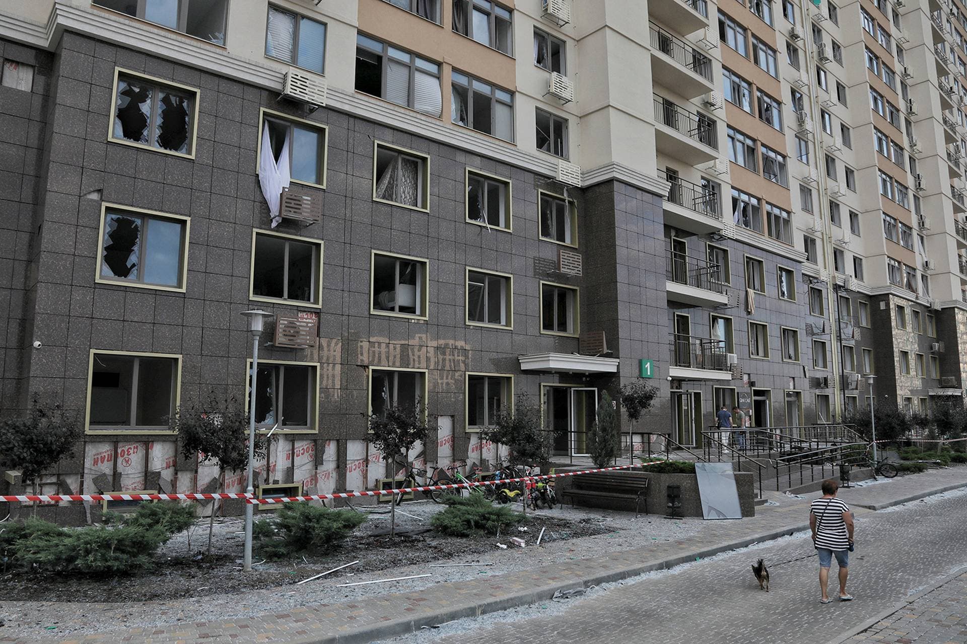 A resident walks with a dog next to an apartment building damaged during Russian strikes near Odesa