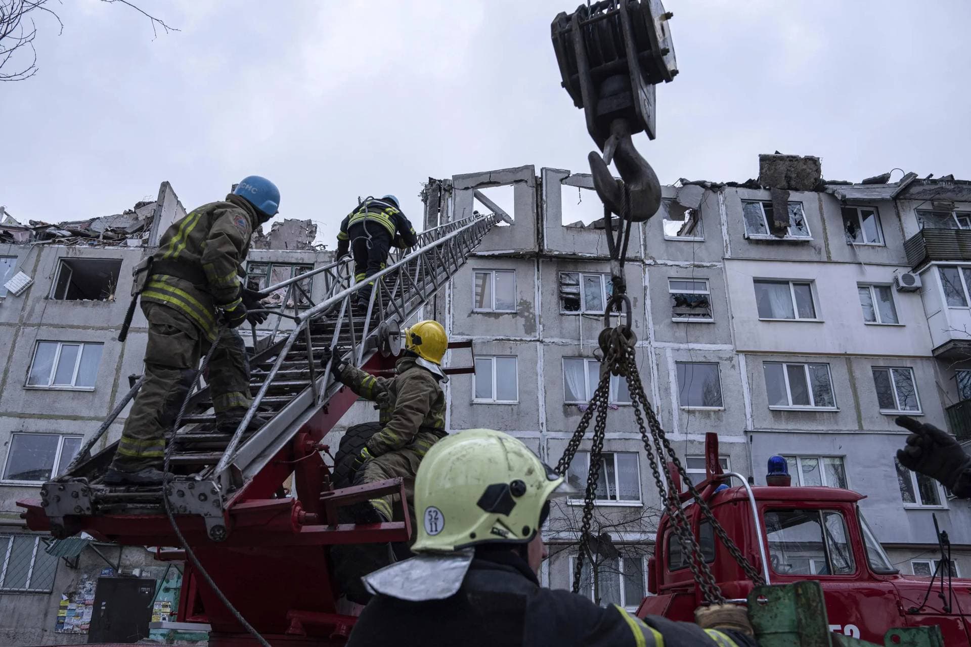 Rescue workers climb by ladder as they clear the rubble of the residential building which was destroyed by a Russian rocket in Pokrovsk