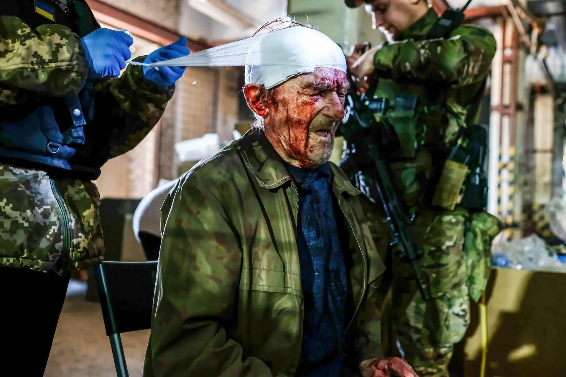 An injured man receives first aid after being hit by Russian shelling at the center of distribution of humanitarian aid in Severodonetsk