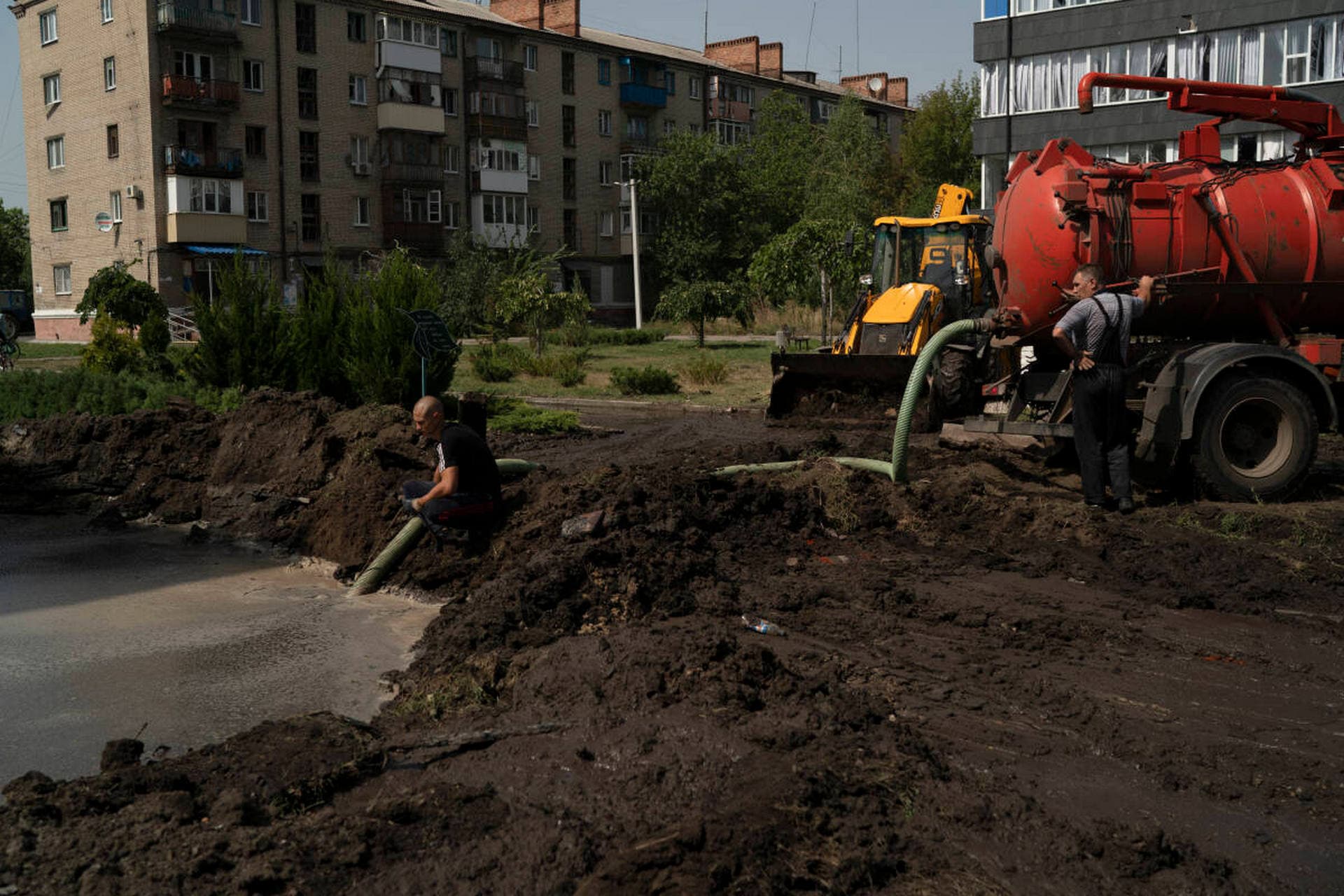 Workers drain water from a crater created by an explosion that damaged a residential building after a Russian attack in Slovyansk