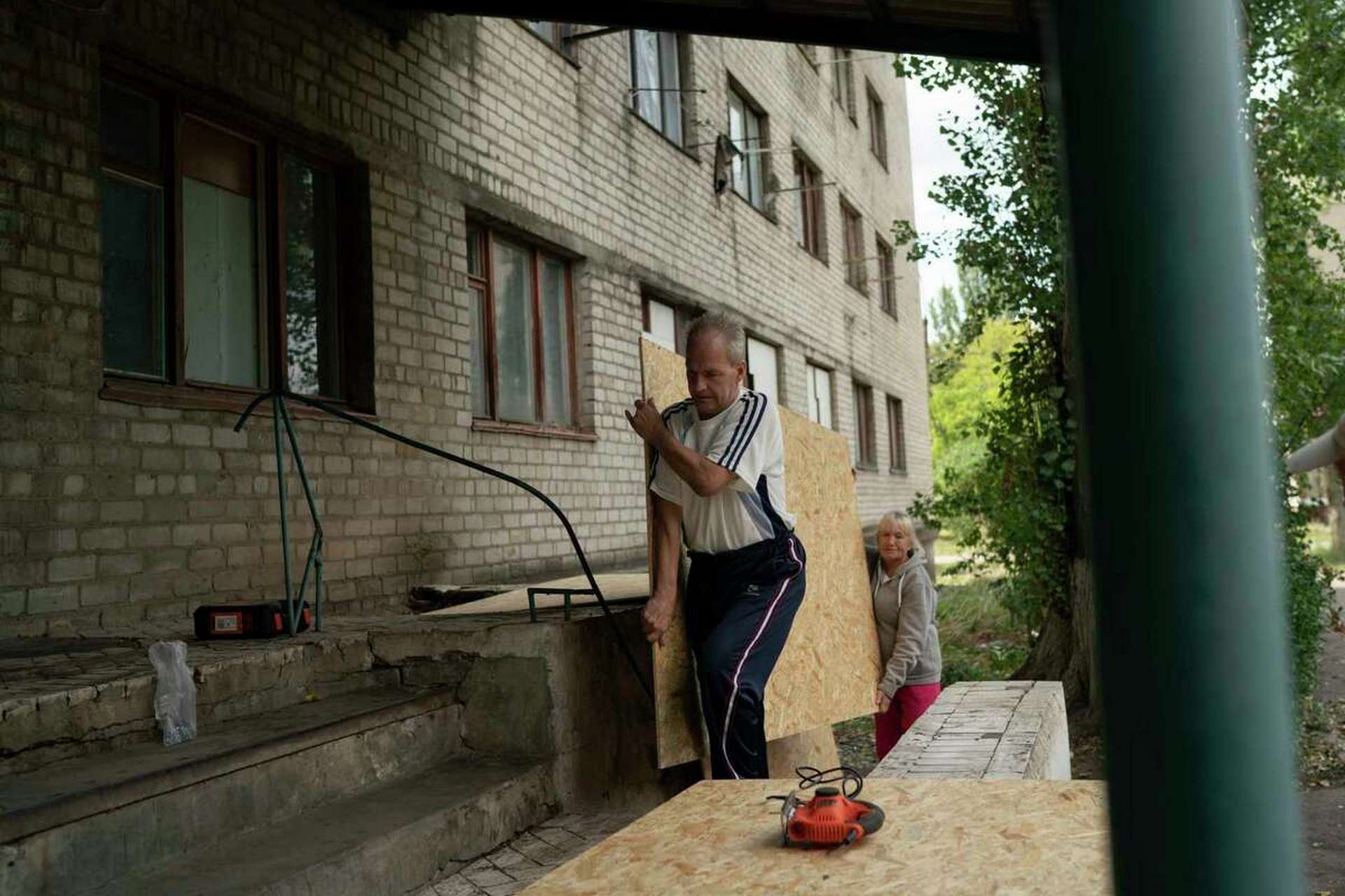 Henadii Sydorenko carries a piece of plywood to cover the windows of apartments that have been damaged after a Russian attack yesterday near a residential area in Sloviansk
