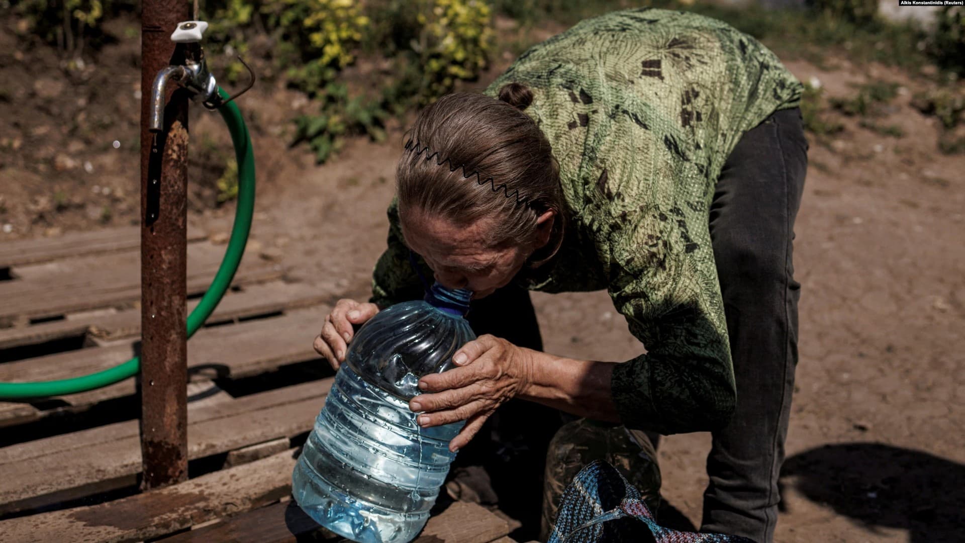 A woman drinks clean water from a canister she just filled up in the eastern city of Slovyansk