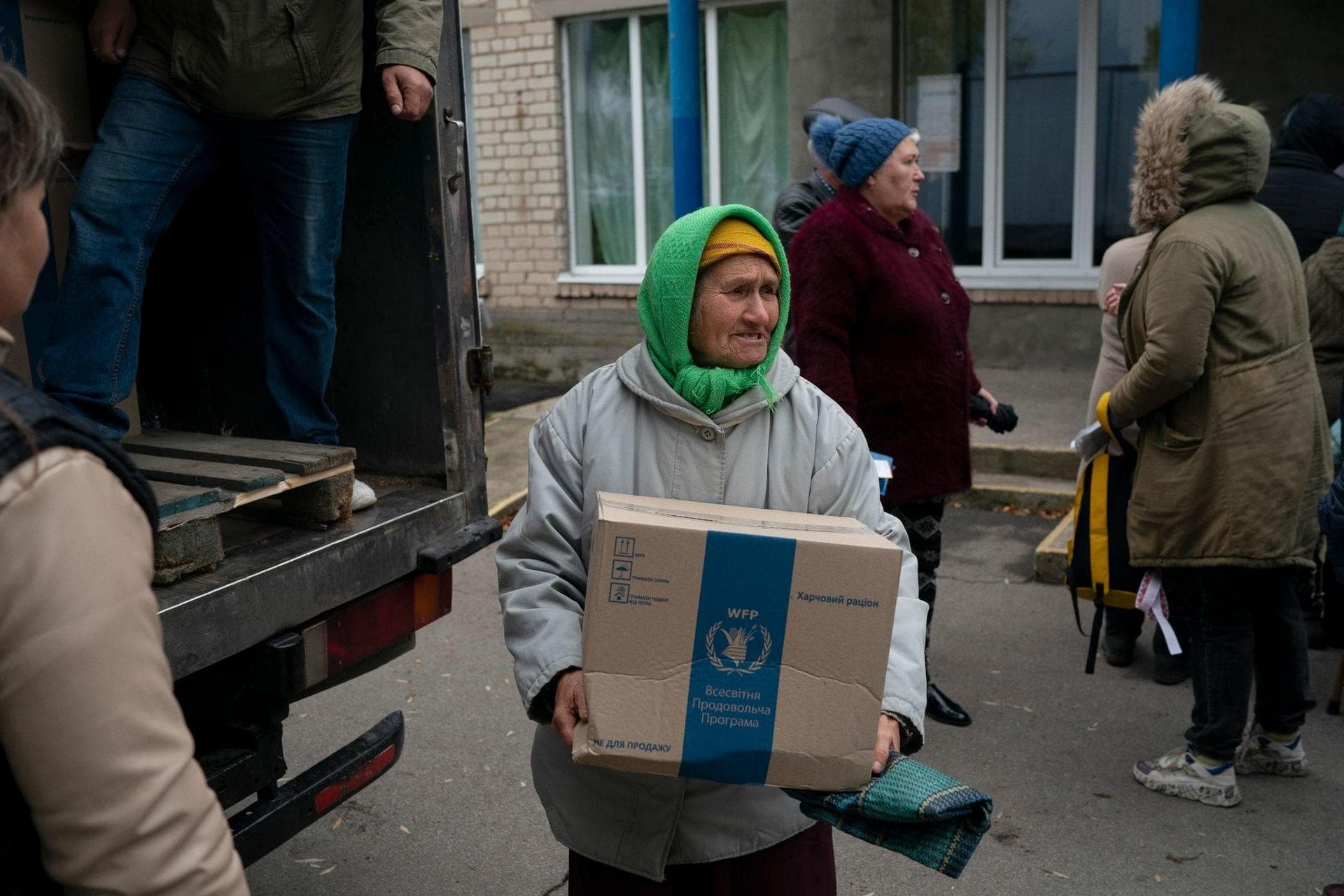 An elderly woman carries a box as humanitarian aid is distributed at the village of Mykhailo Lukasheve