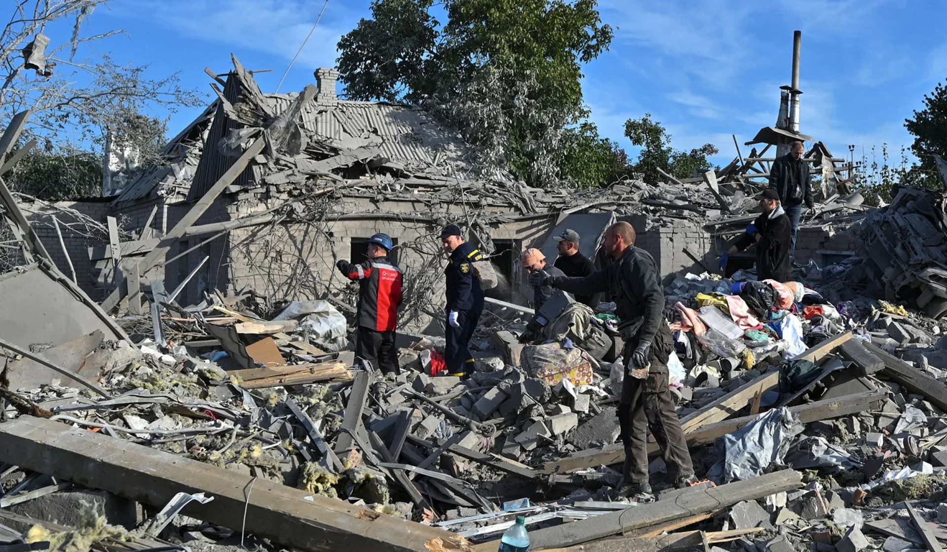 Rescuers and local residents remove debris at a site of a residential area heavily damaged by a Russian missile strike in Zaporizhzhia