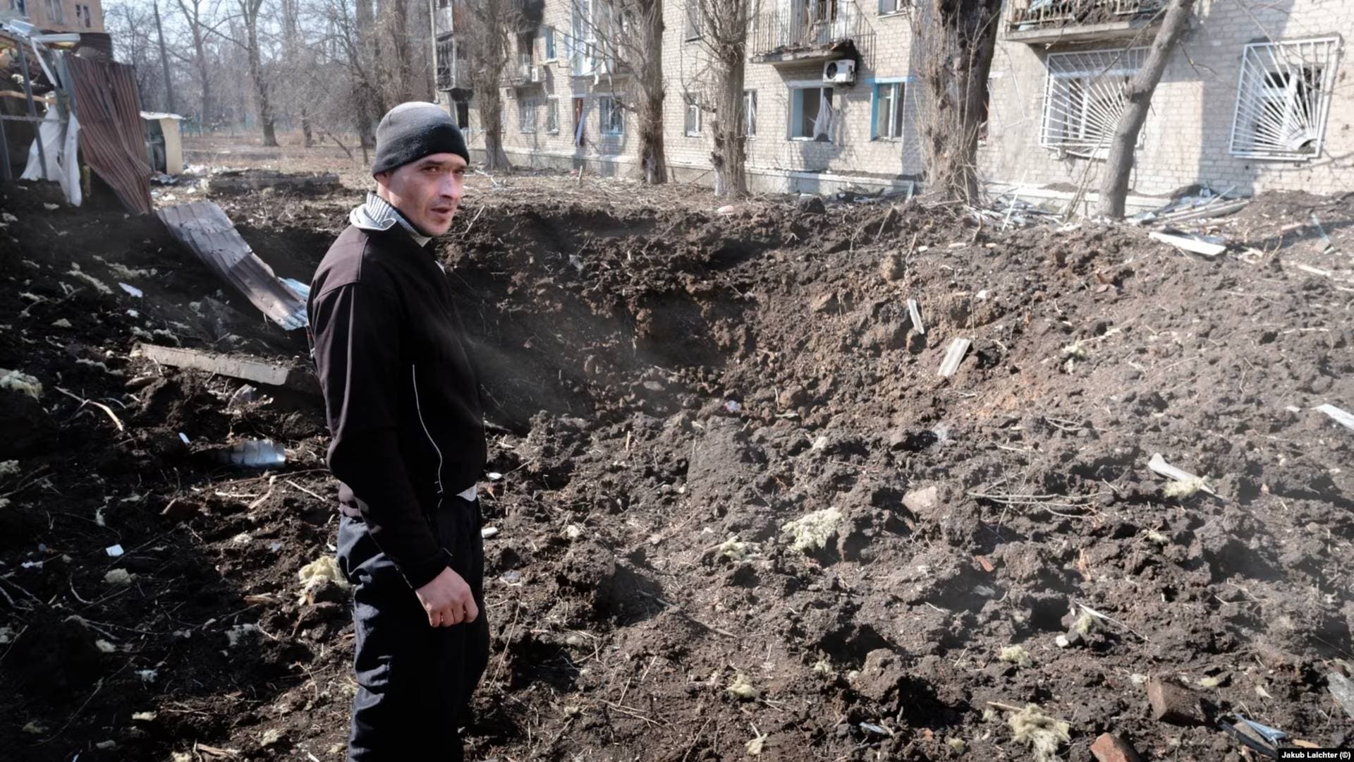 A man in Avdiyivka inspects a fresh crater after Russian shelling in the center of his hometown