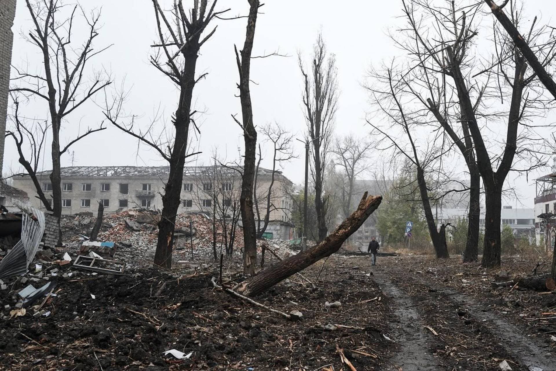 A local resident walks amongst damaged residential buildings in the town of Avdiivka