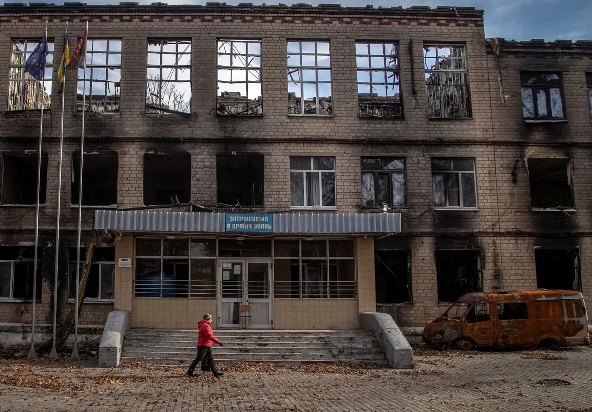 A local resident passes by a school destroyed by Russian shelling in Avdiivka