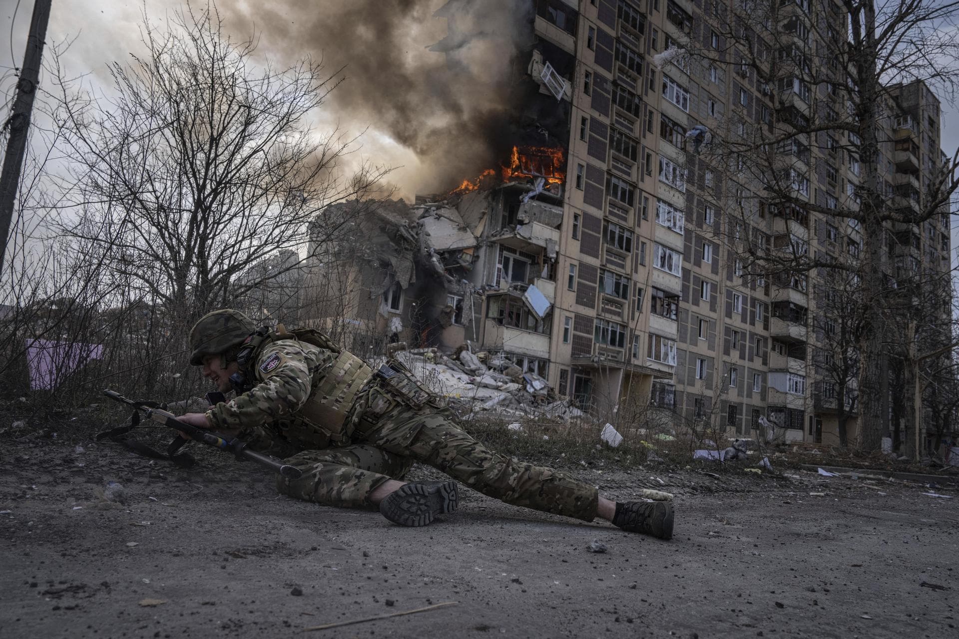A Ukrainian police officer takes cover in front of a burning building in Avdiyivka