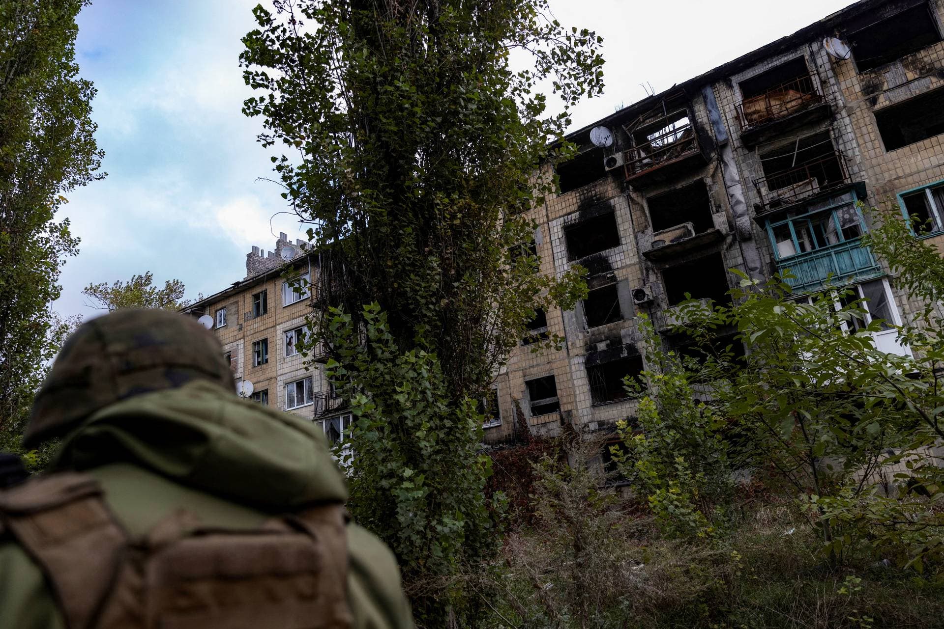 A police officer walks near a damaged residential building in the town of Avdiivka