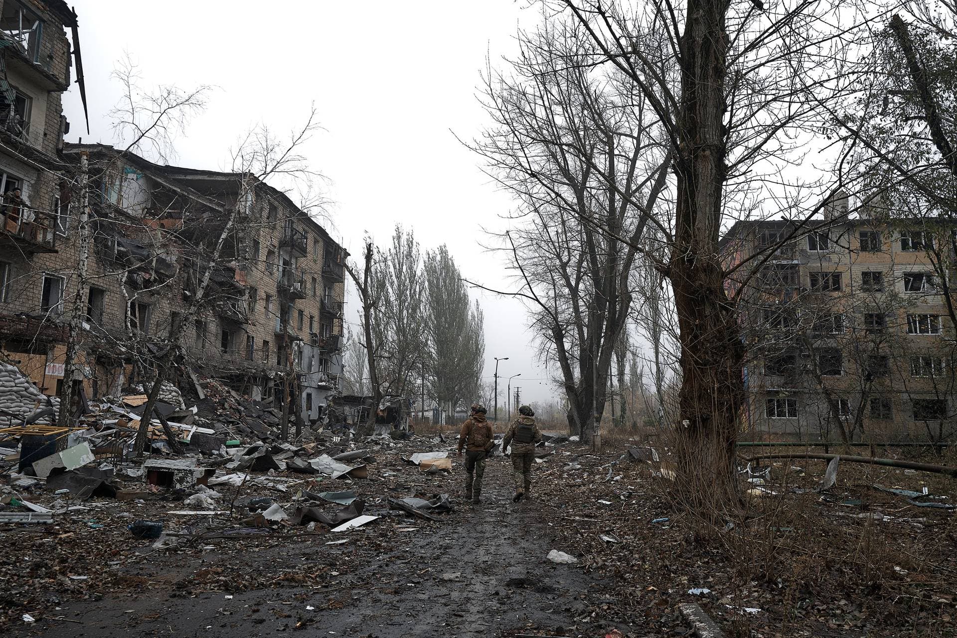 Two Ukrainian soldiers walk along the destroyed city in the fog in Avdiivka
