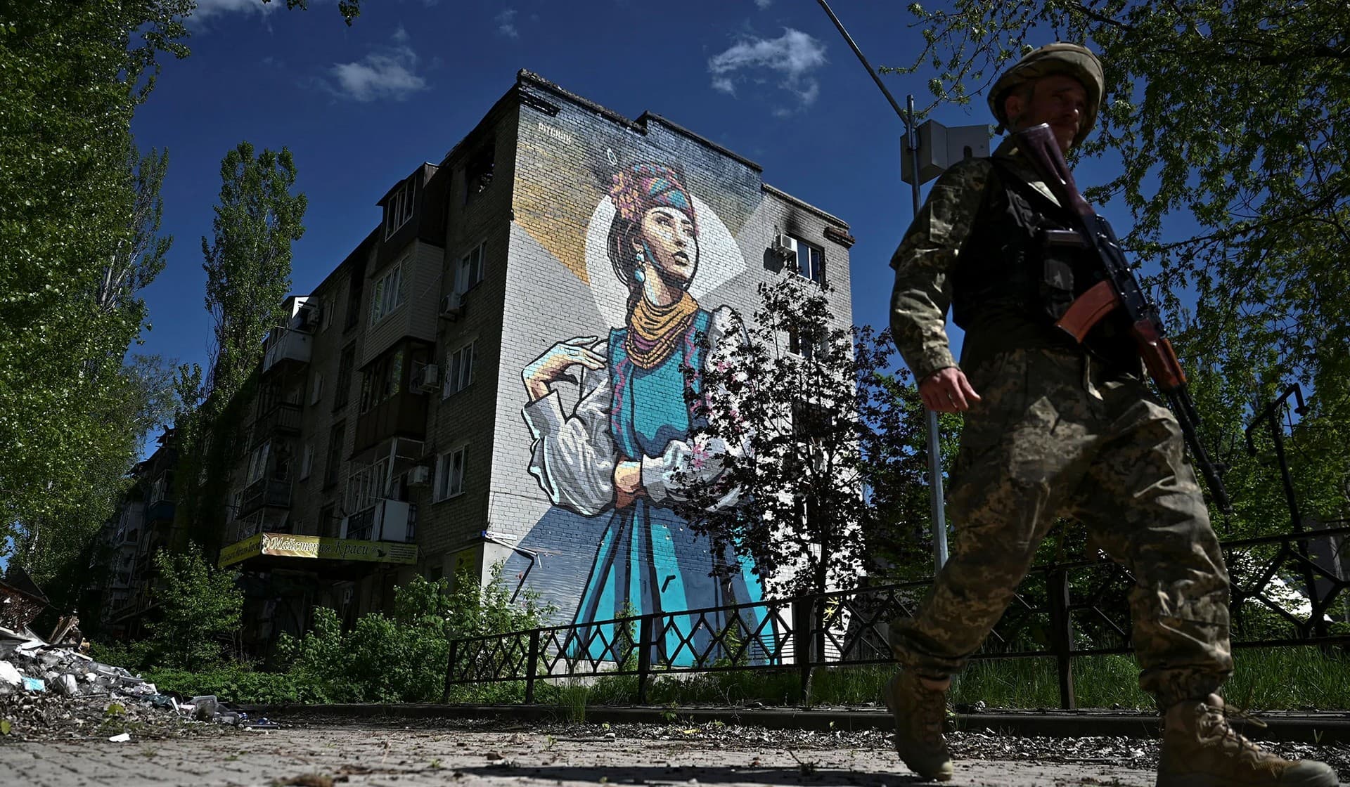 A Ukrainian serviceman walks past a residential building damaged by a Russian military strike in the town of Avdiivka