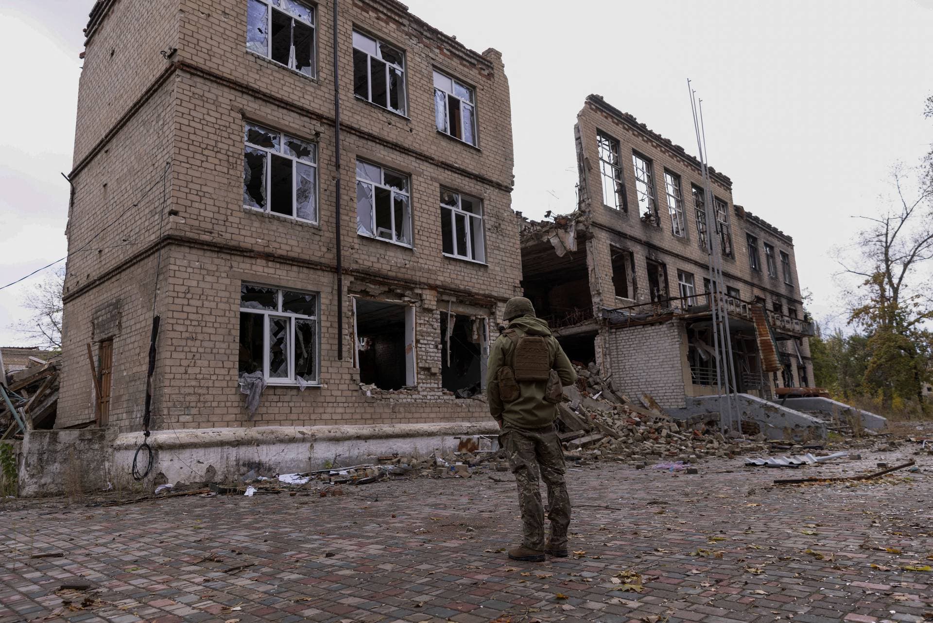 A police officer stands in front of a damaged building in the town of Avdiivka