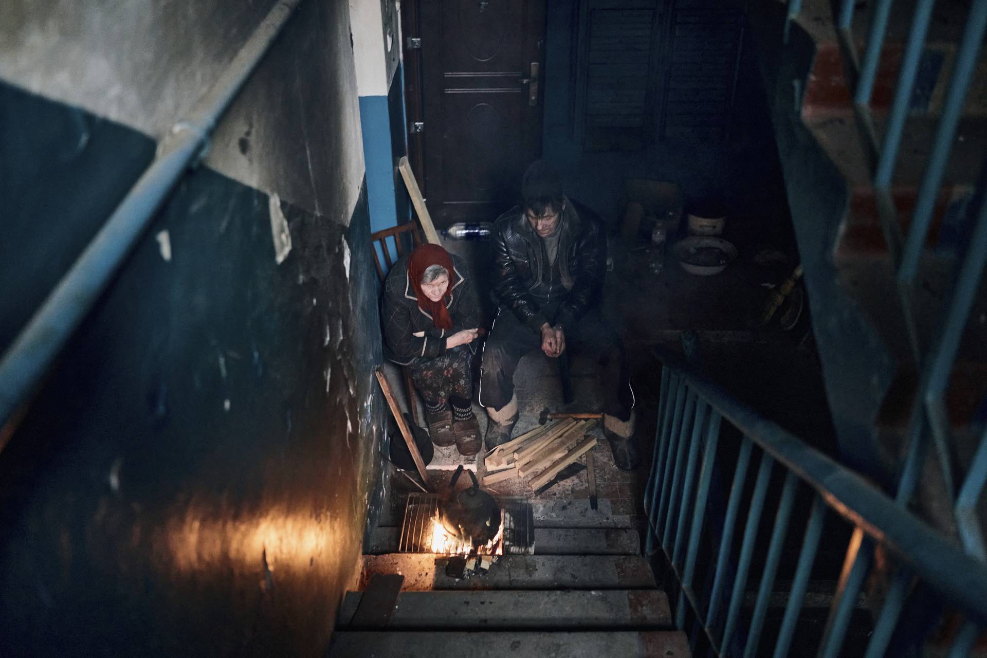 Local residents cook on the stairs of an apartment house in Chasiv Yar