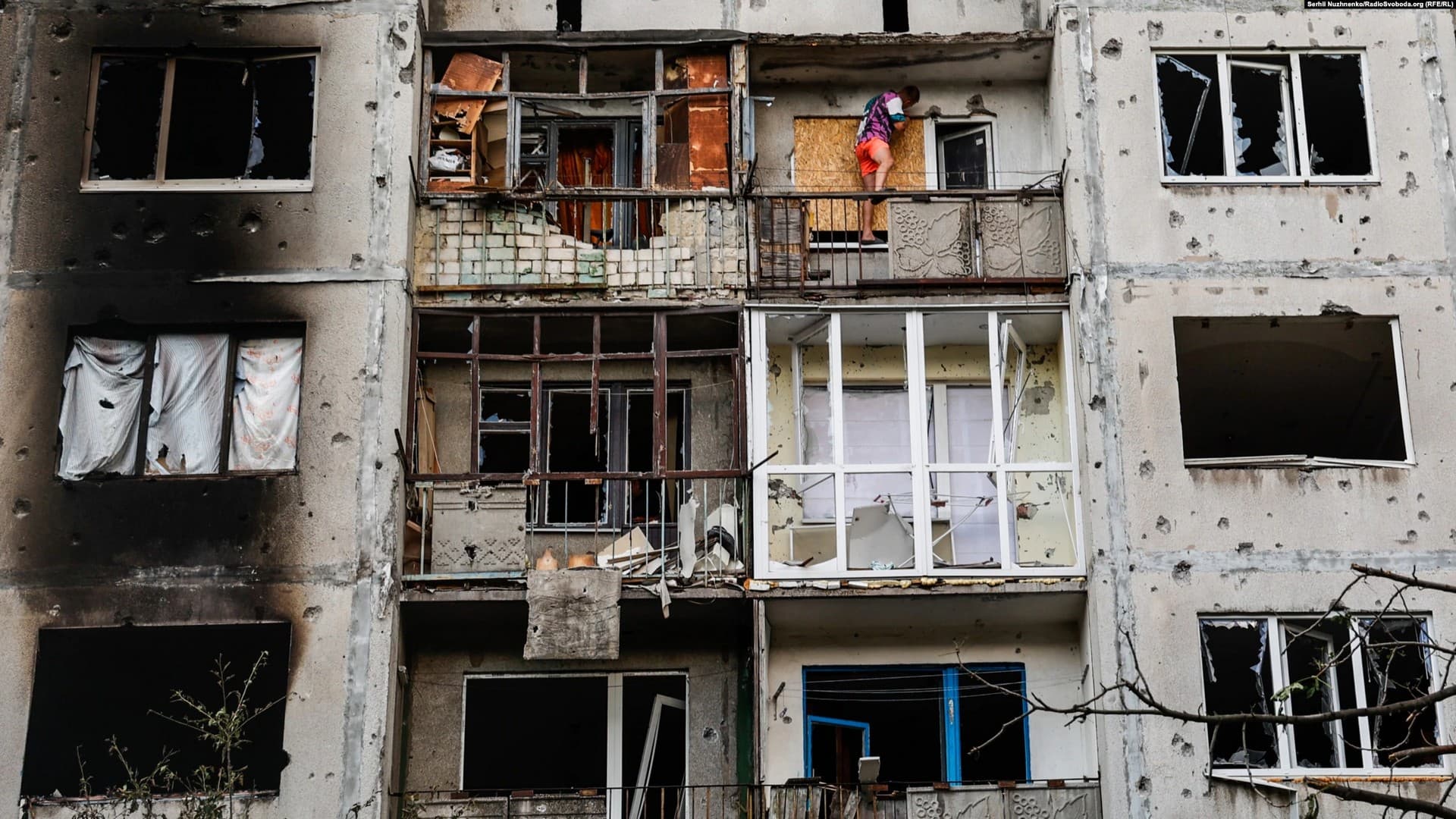 A man replaces a shattered window in an apartment building damaged by the Russian missile strike in Bakhmut