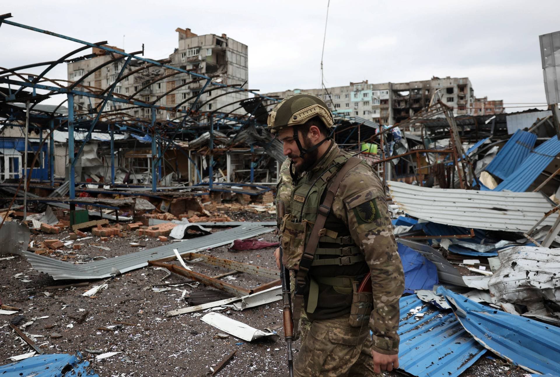 A Ukrainian serviceman walks near residential buildings damaged by shelling in the front-line city of Bakhmut