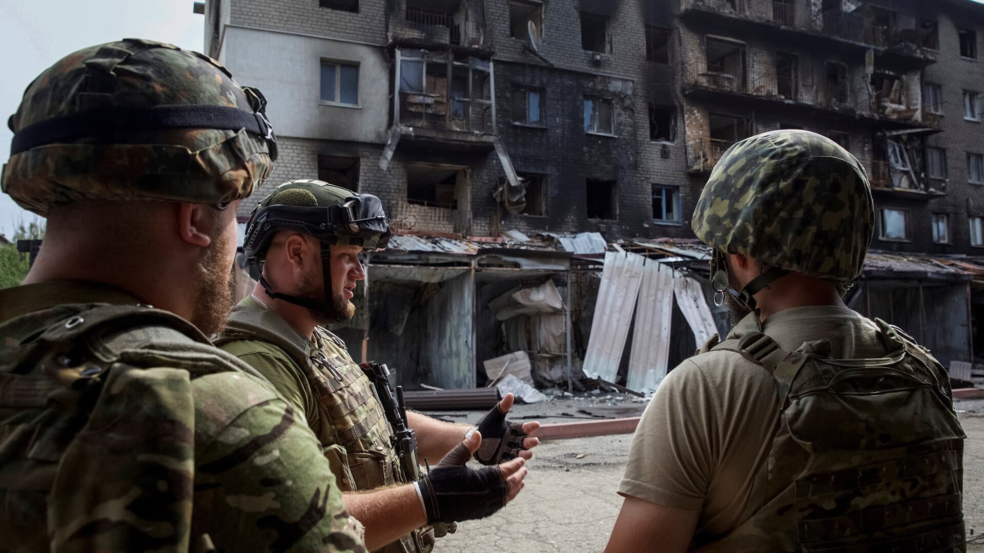 Ukrainian service members in front of a residential building damaged by a Russian military strike in Siversk