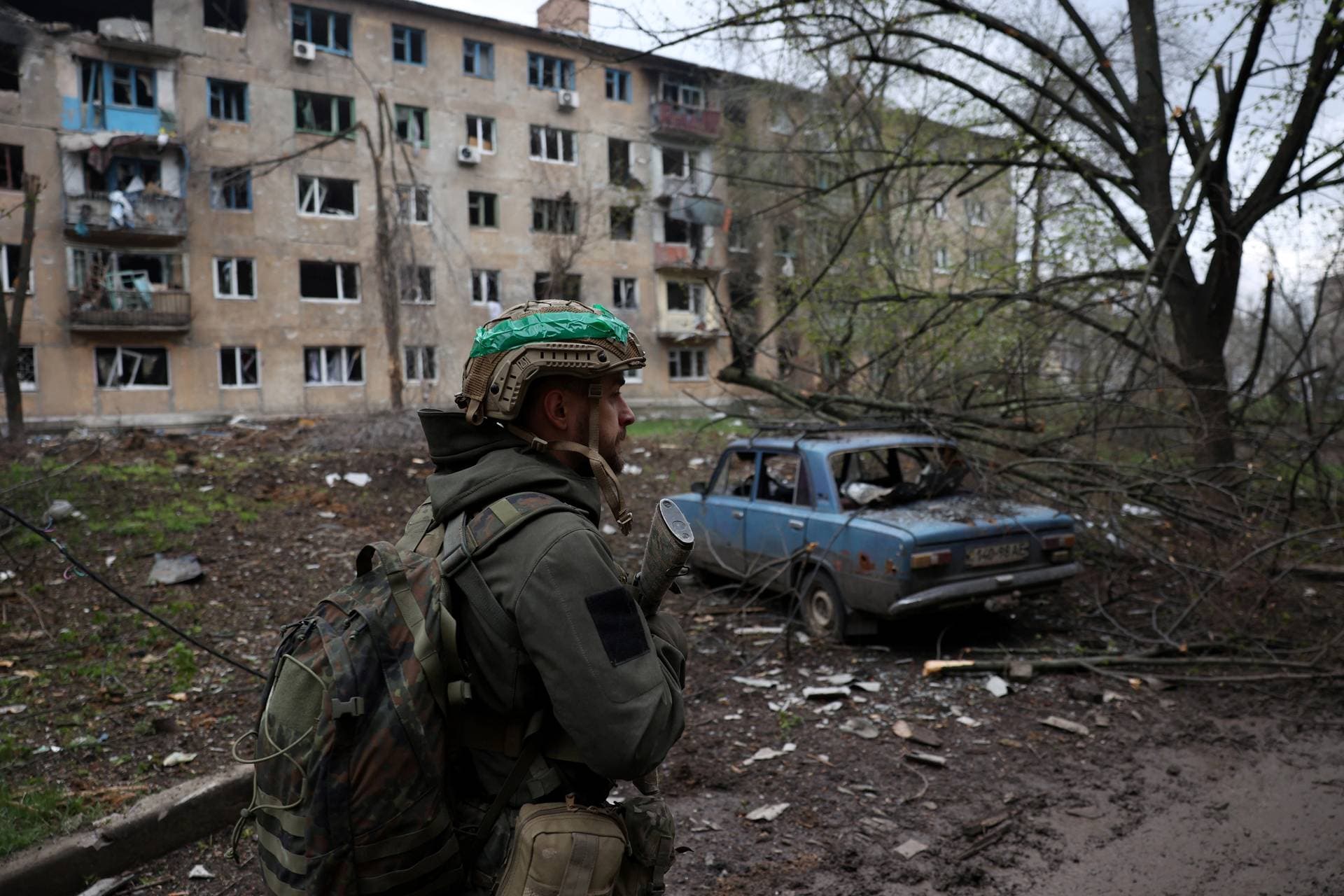 A Ukrainian serviceman walks near a residential building damaged by shelling