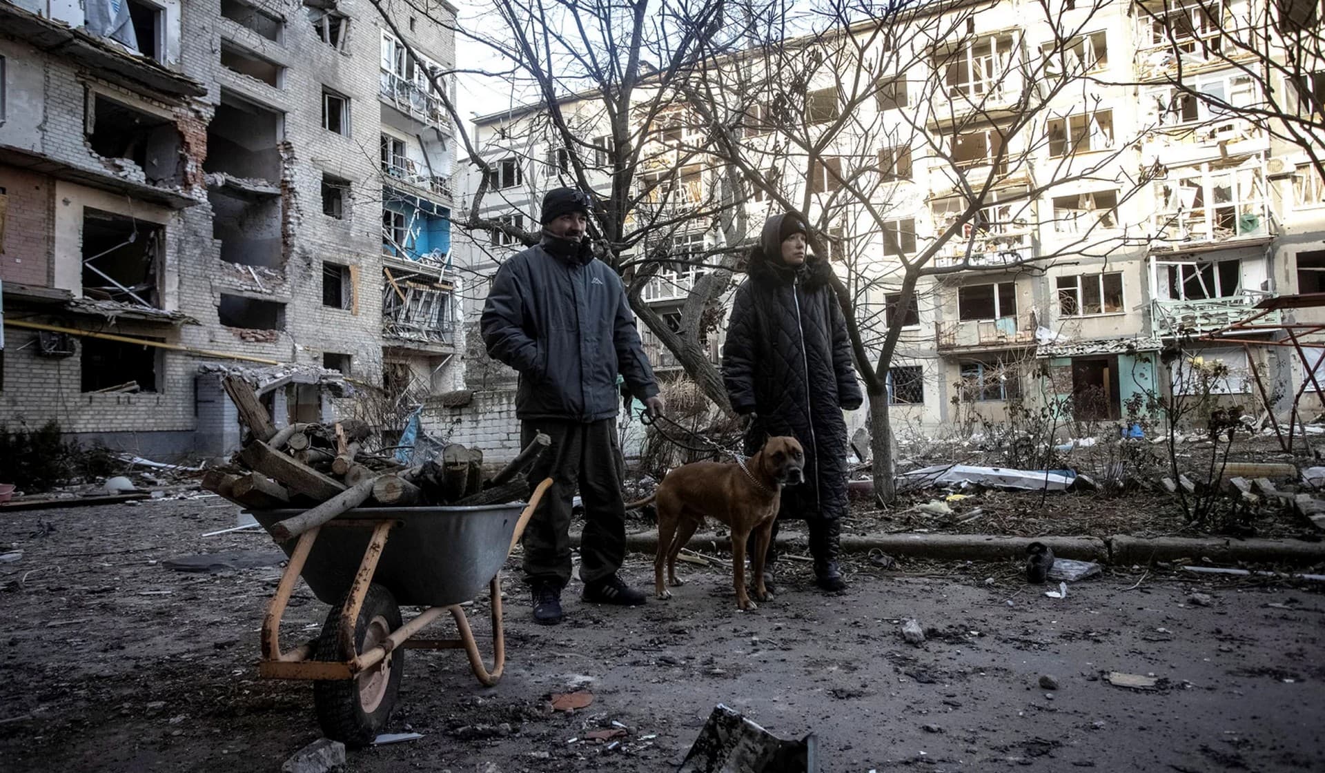 Local residents stand in the yard of their destroyed apartment building in Bakhmut