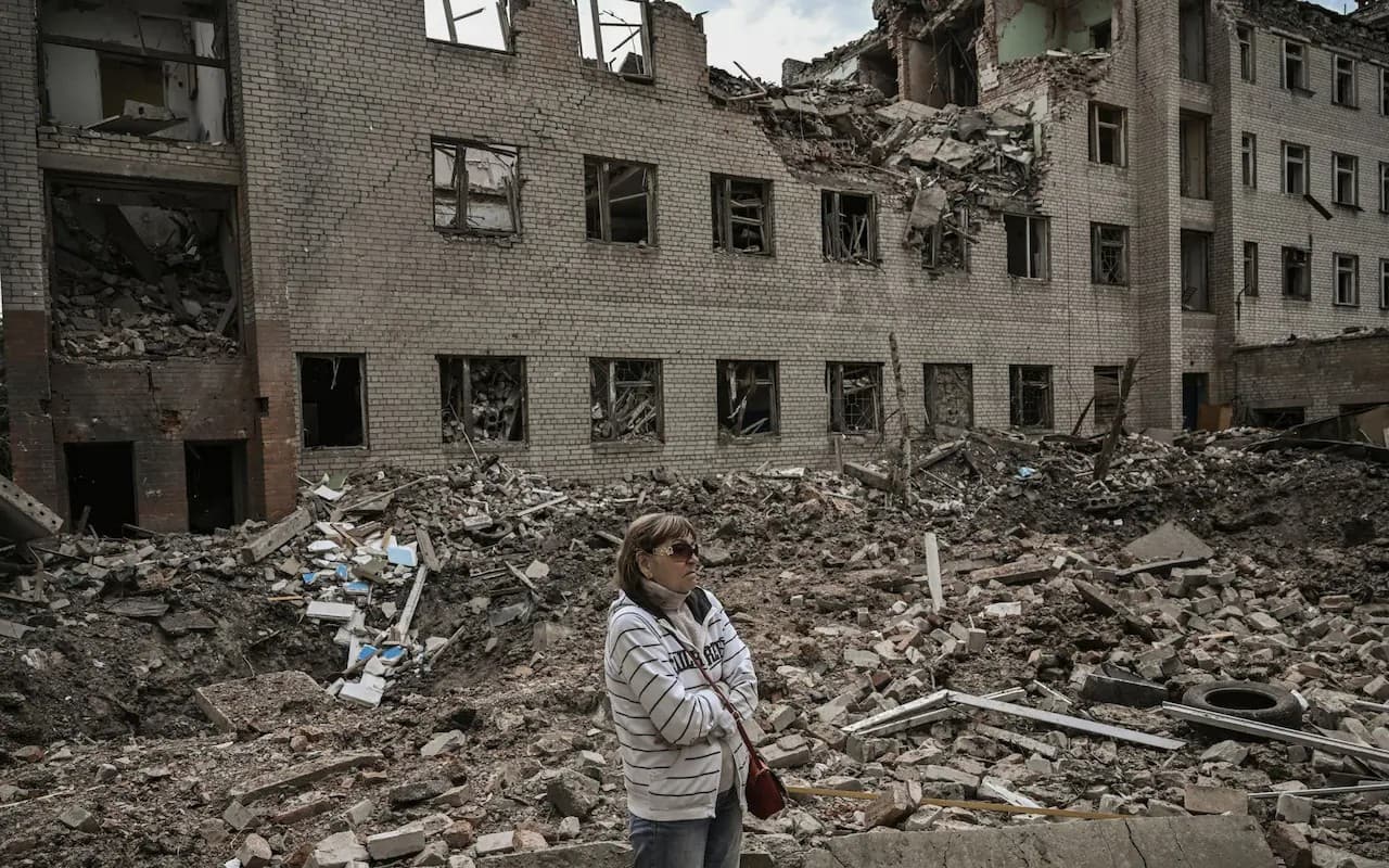 A woman stands in front of a destroyed administration building in the city of Bakhmut